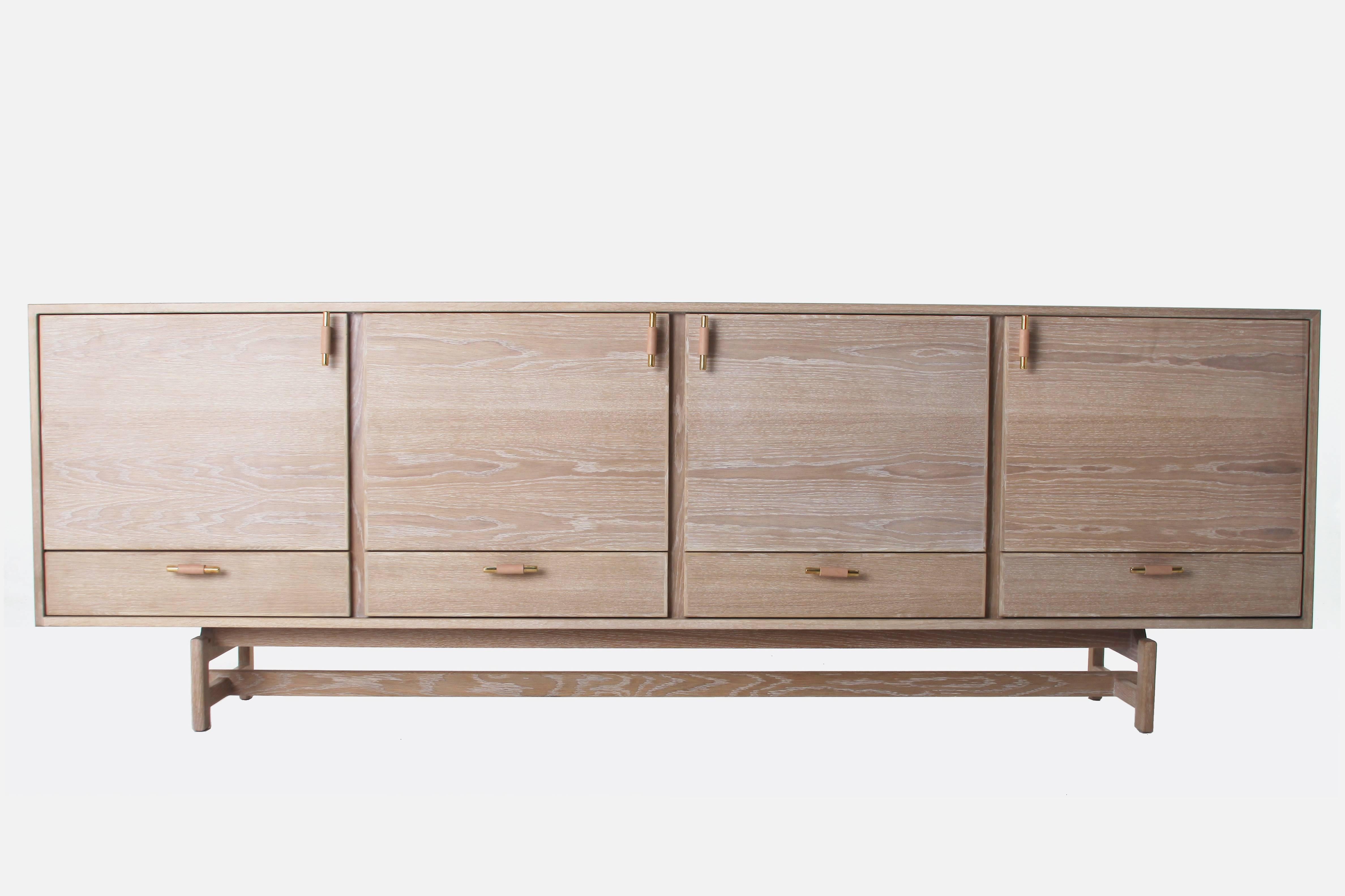 The Josephine Credenza with a wood base comes in walnut or oak with a variety of finish options. Pulls are steel or brass wrapped in leather. Various combinations of the slatted media cabinet doors, regular doors, and drawers are available. 

Please