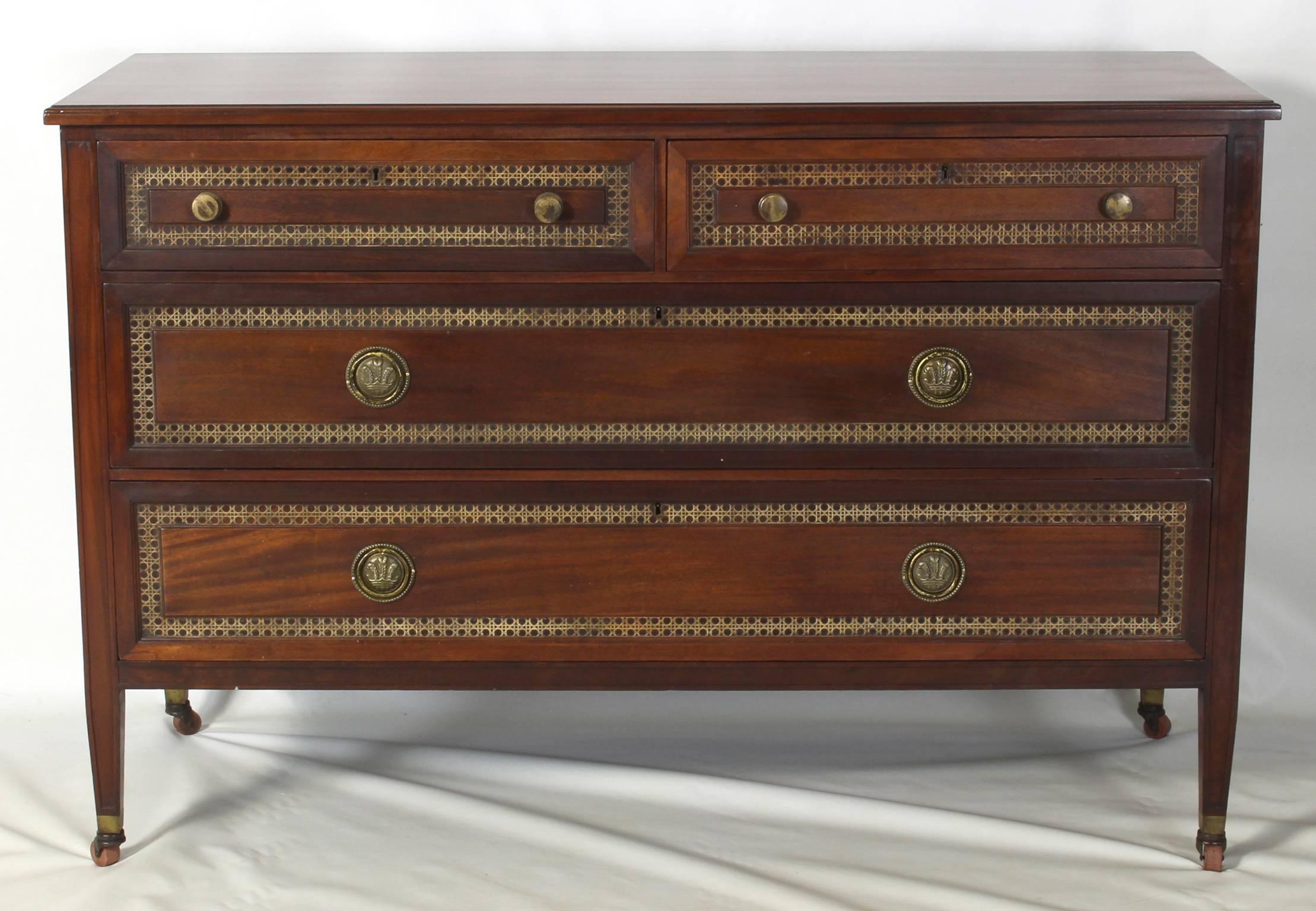 An early 20th century American made commode or chest of drawers made of solid mahogany accented with cane inset panels and hand-cast brass pulls.