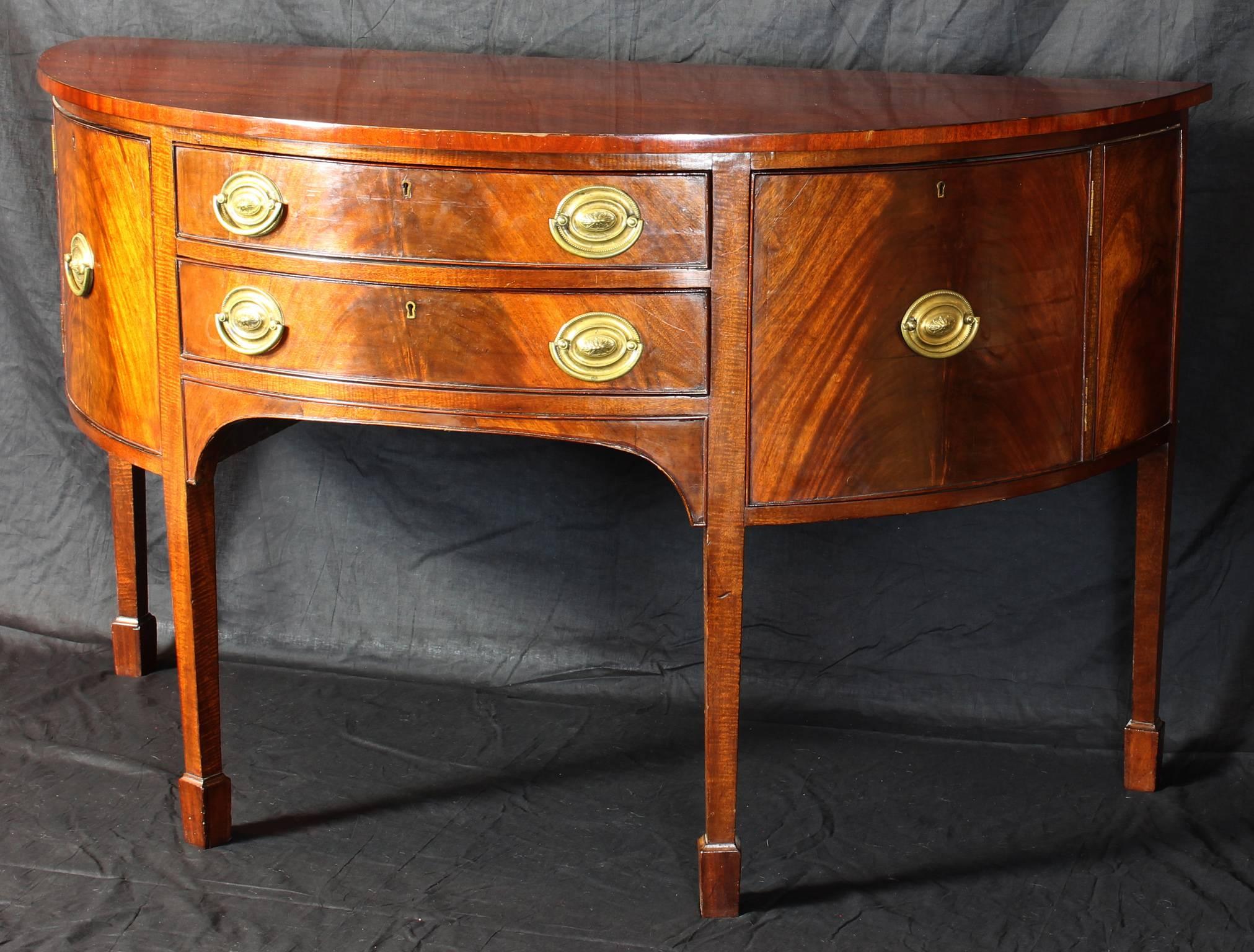 A late 18th century English mahogany demilune sideboard with original brass pulls.