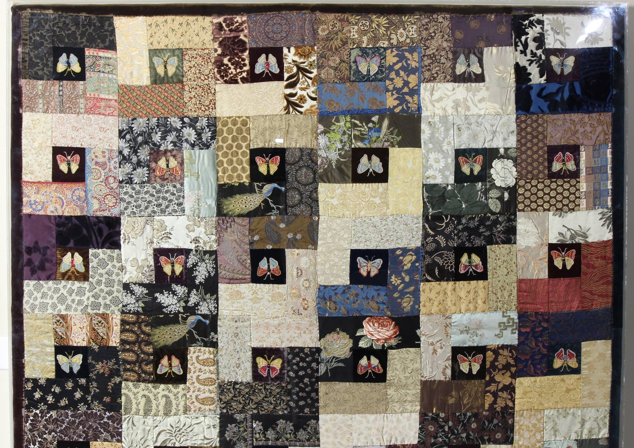 A charming late 19th century crazy quilt done in embroidered silk and velvet squares depicting butterflies, peacocks and flowers. The quilt is nicely mounted in a Lucite frame for hanging.