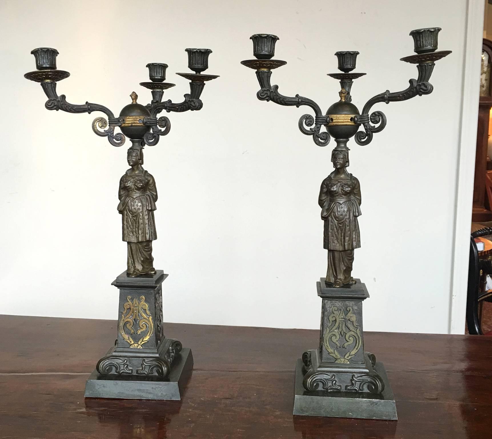 A large and impressive pair of mid-19th century cast iron and bronze candelabra depicting classical female figures.