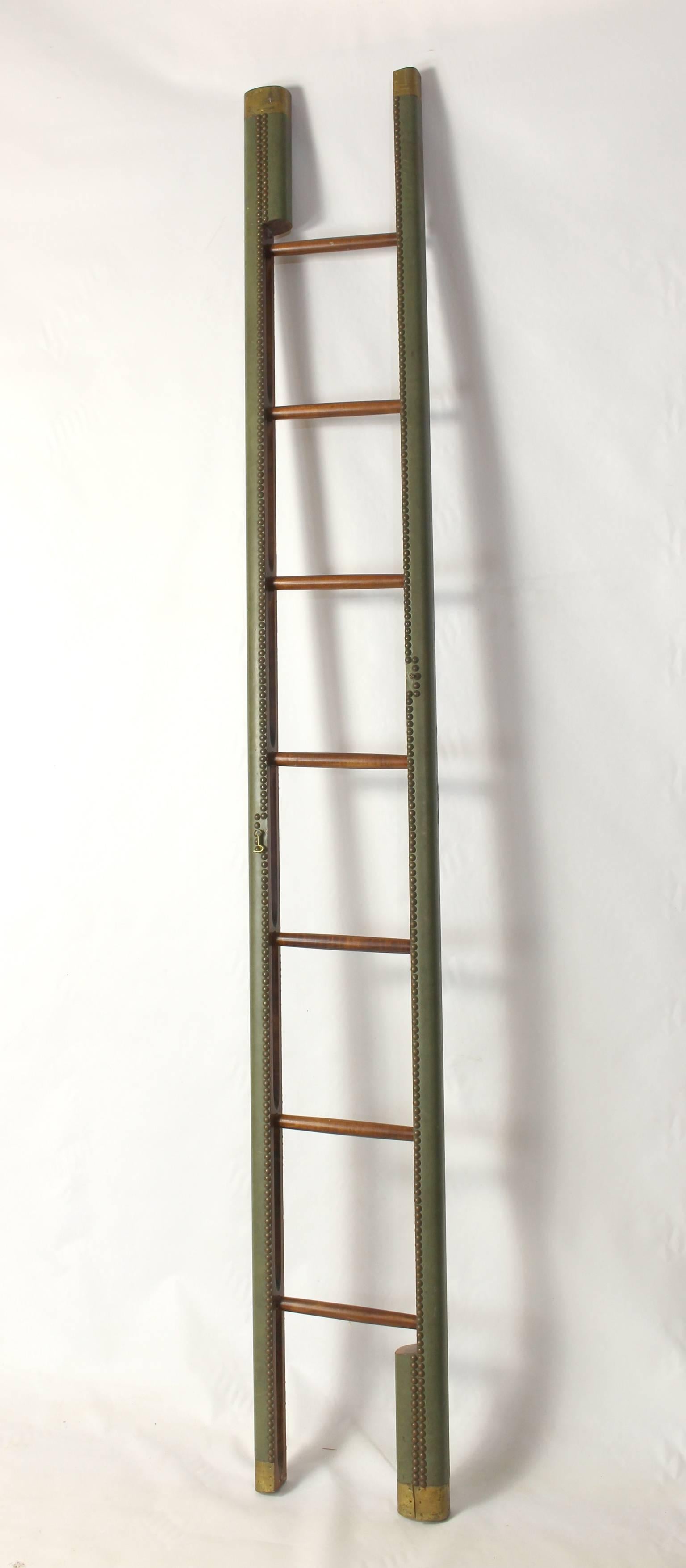 A Classic English folding pole or library ladder covered in a soft moss green leather accented with brass tacks.