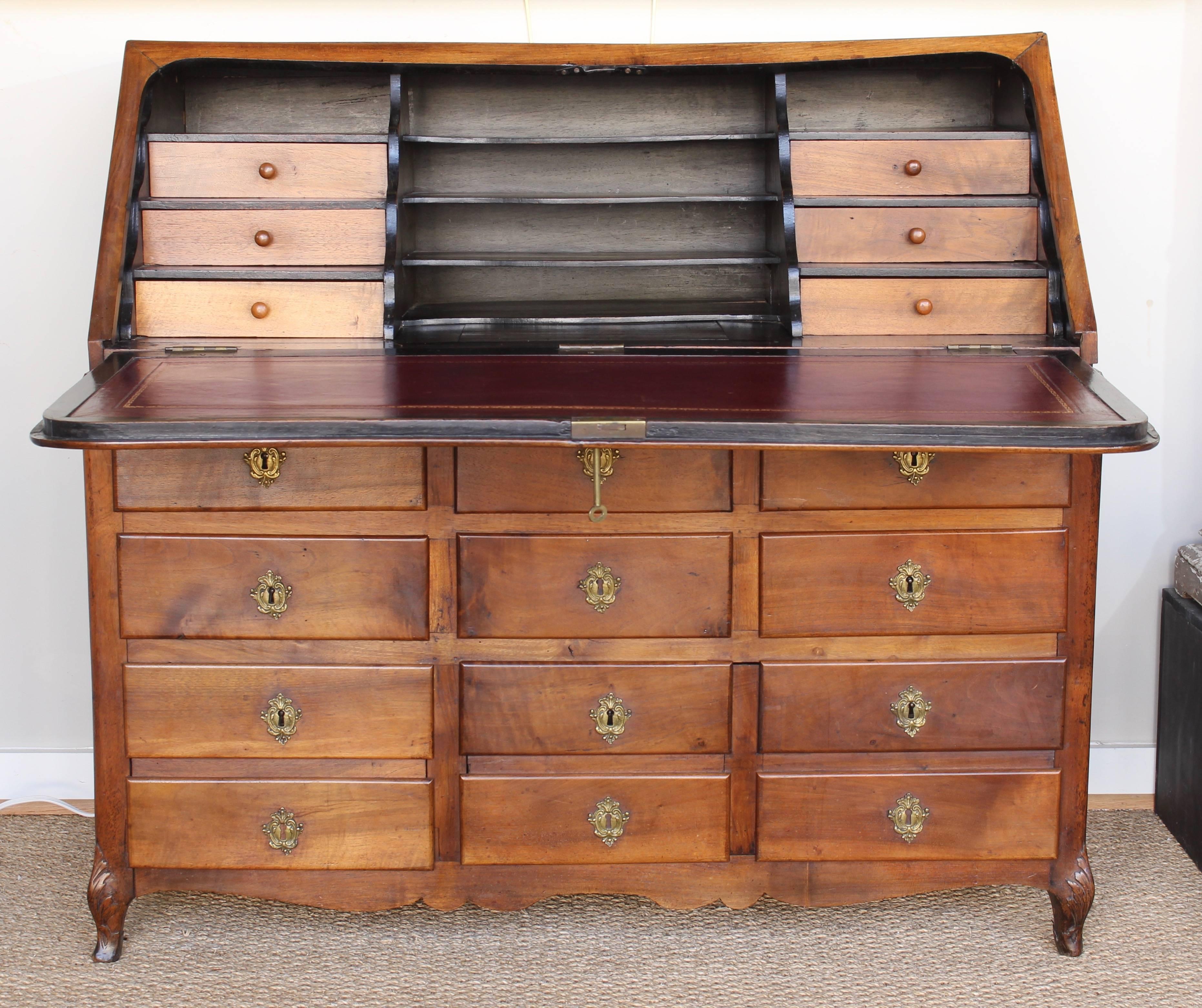 An exceptional late 18th century French Provincial fruitwood drop front desk with twelve visible drawers and a multitude of shelves, drawers and secret compartments behind the drop front with red tooled leather writing surface.