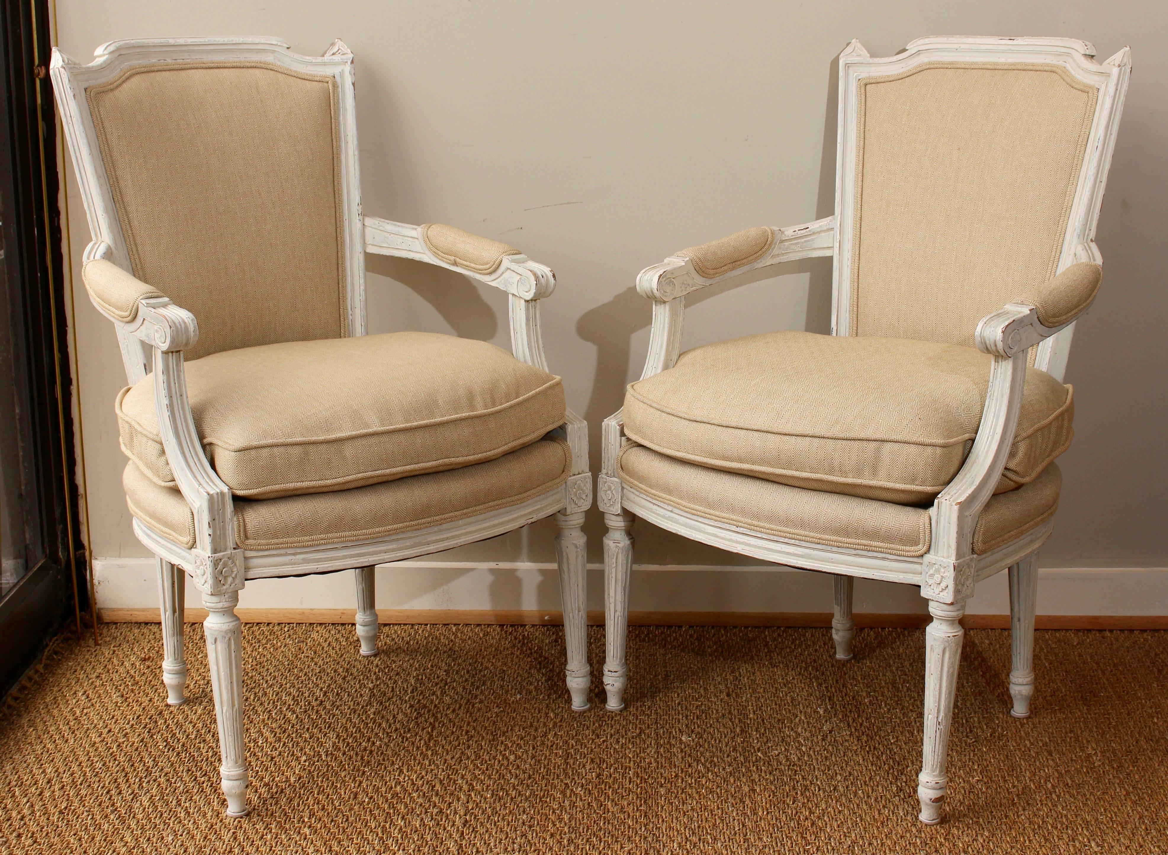 An early 20th century pair of hand-carved and painted French fauteuils newly upholstered in Italian linen with down-filled cushions.