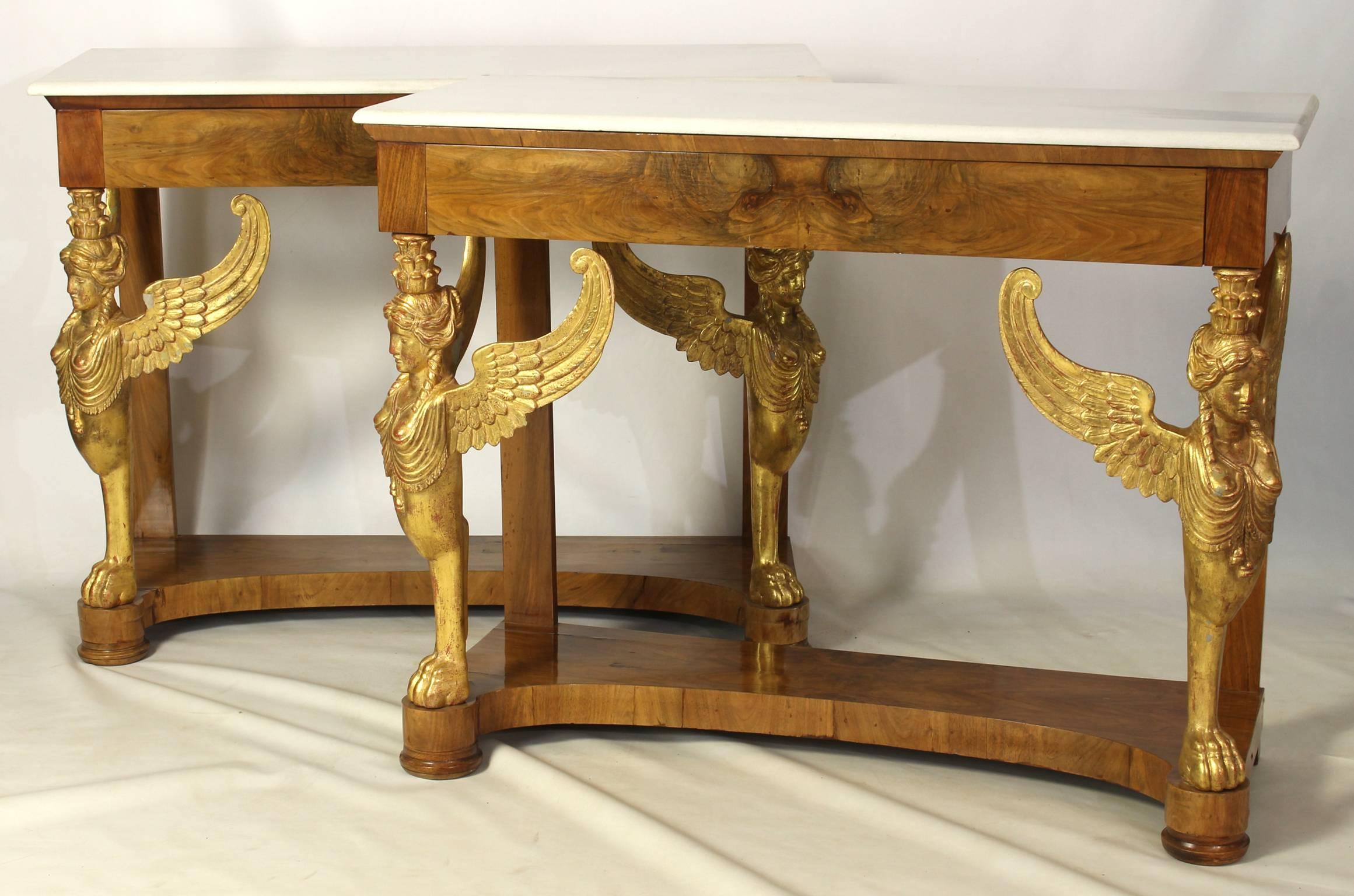 An elegant pair of late 19th century Italian neoclassical walnut and parcel gilt console tables with white marble tops supported by intricately carved winged female griffins.
