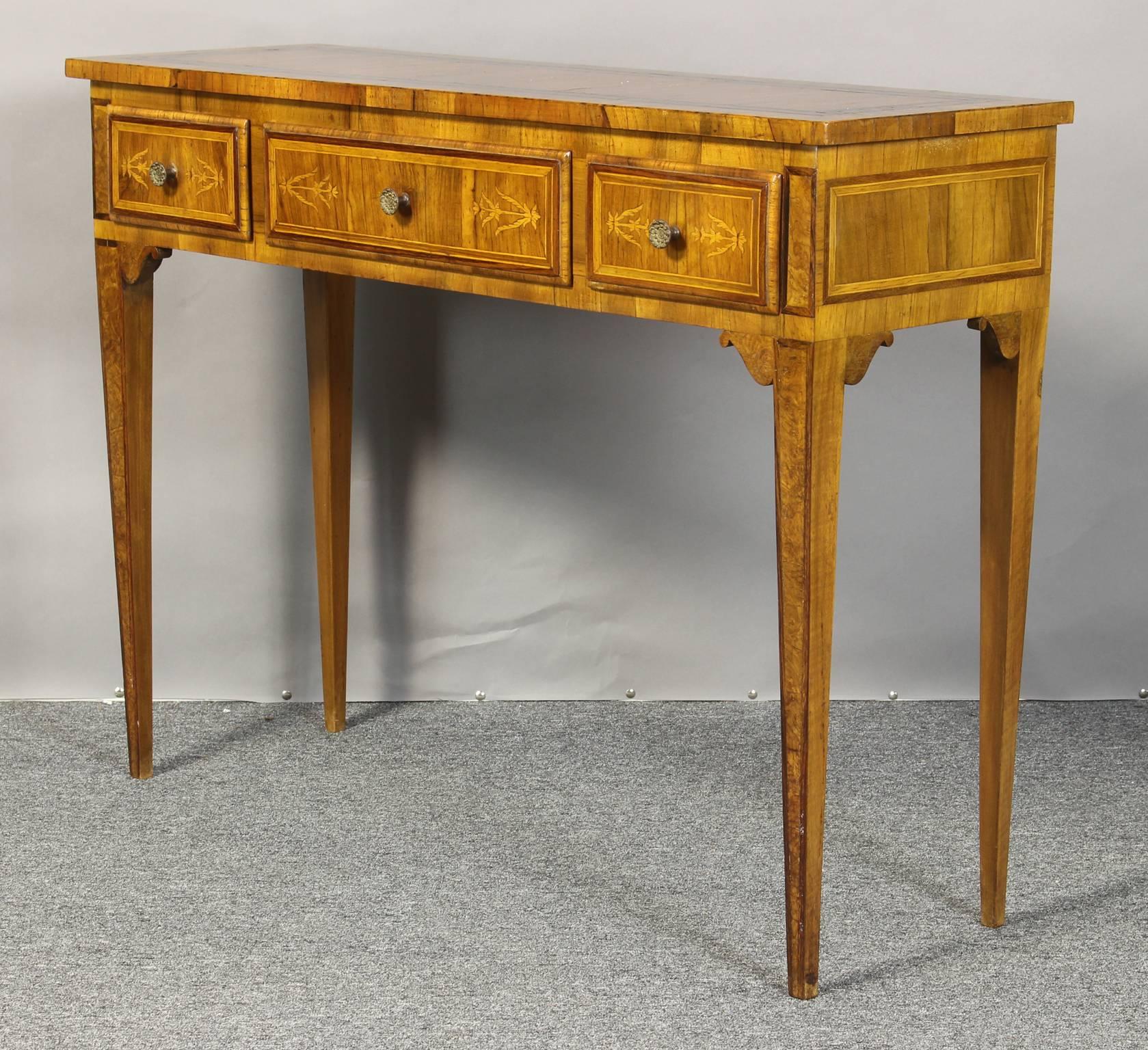 A small mid-20th century Italian marquetry console table featuring one long centre drawer with two smaller flanking drawers on square tapering legs.