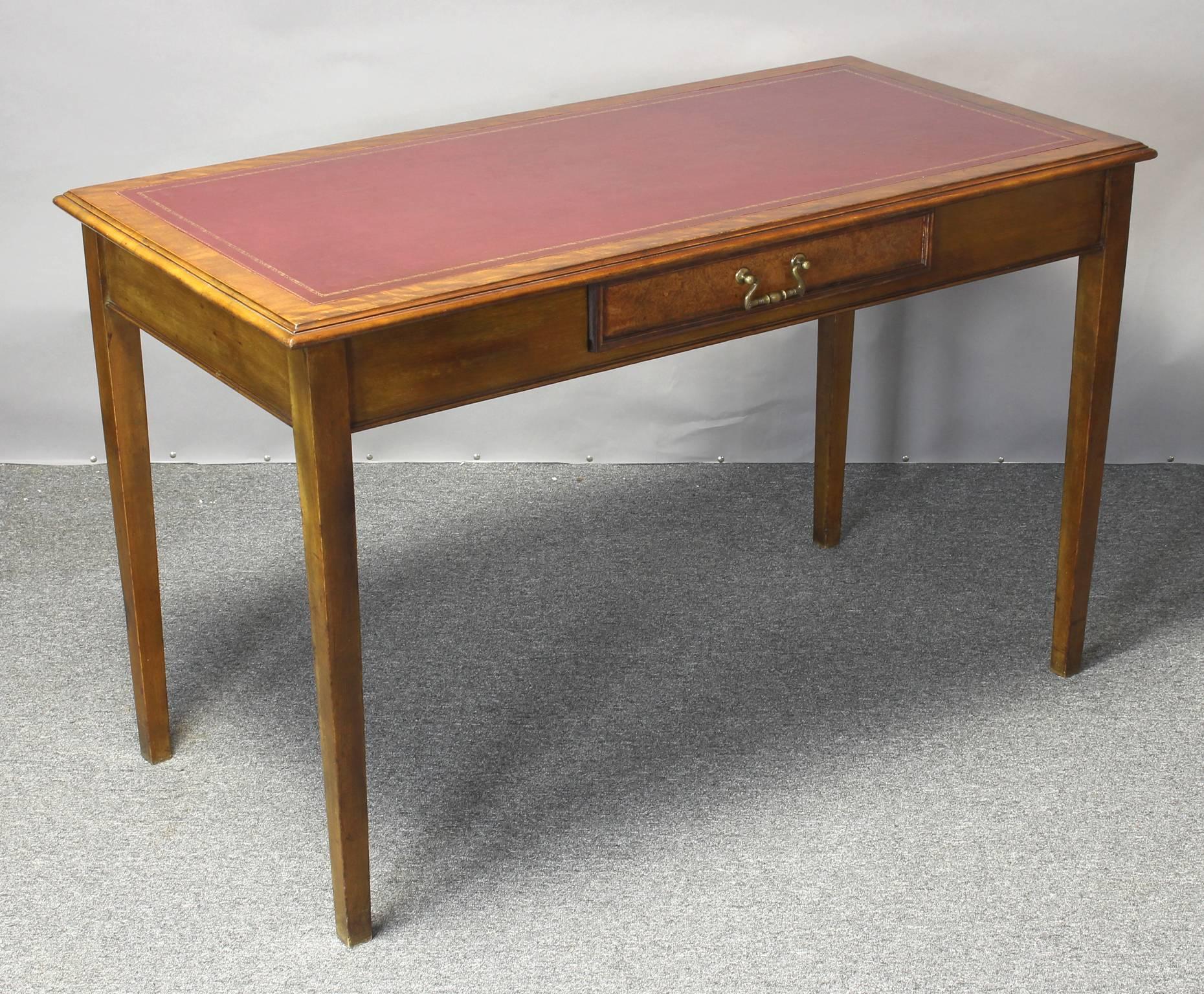 A simple and elegant late 19th century English Edwardian writing table with inset red leather top above a single drawer resting on square tapering legs.