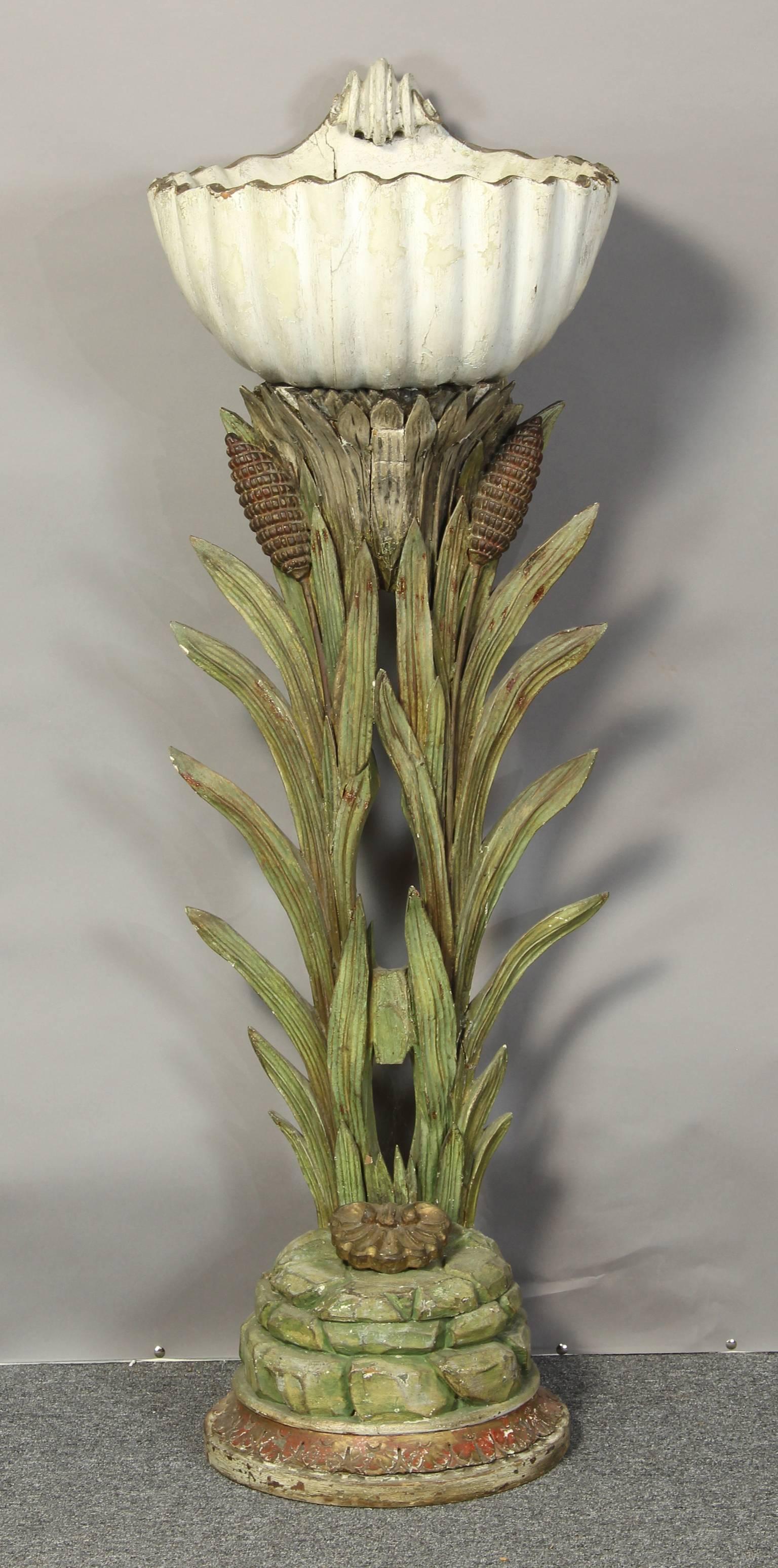 An elegant and unusual Italian carved wood and polychrome decorated baptismal font in the form of lilies supporting a large shell vessel.