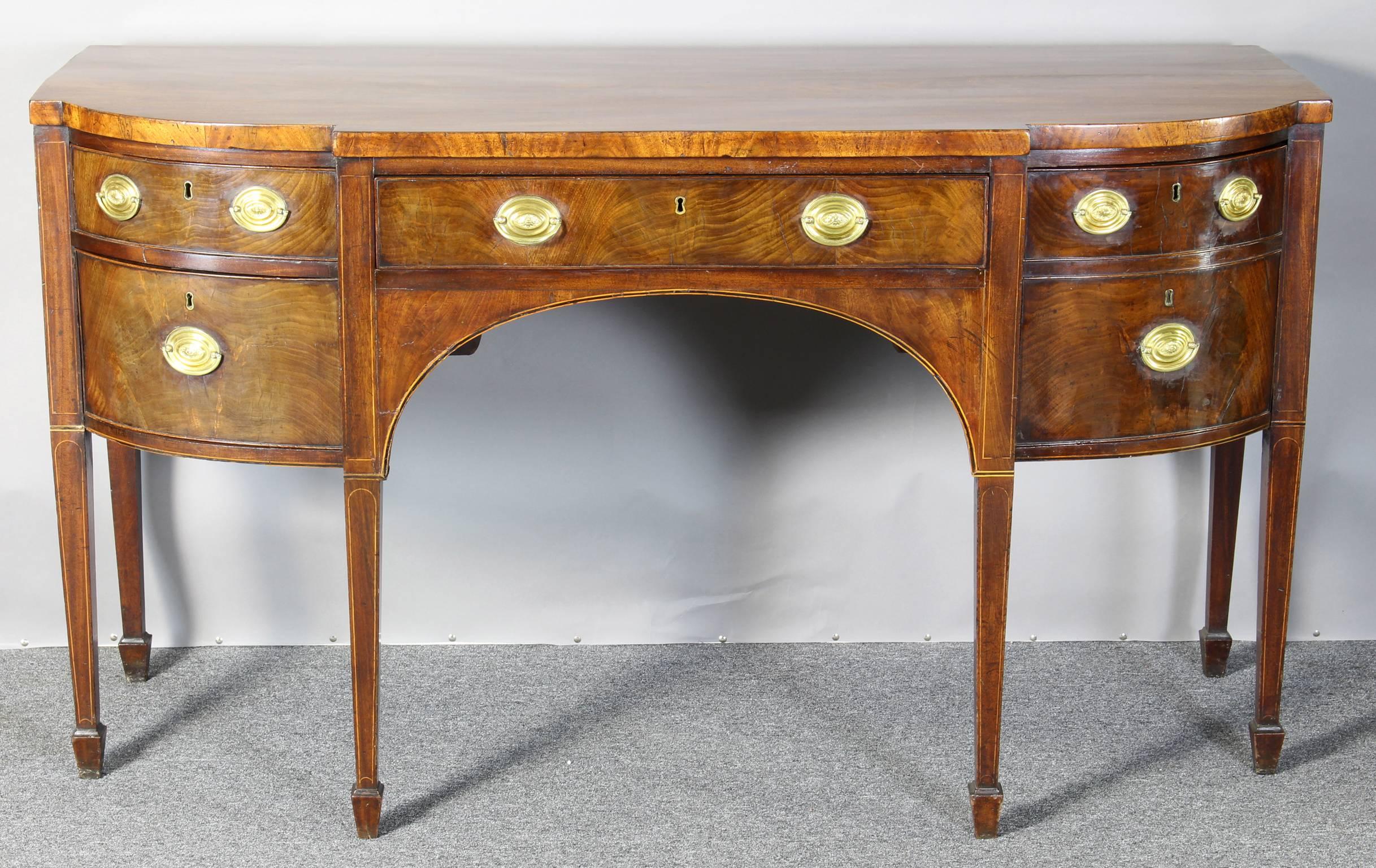 An elegant late 18th century George III mahogany sideboard, of semi-bowed form with boxwood and ebony stringing above a central drawer, an arched apron, twin false drawer front on the side with fitted cellar interior and two corresponding short
