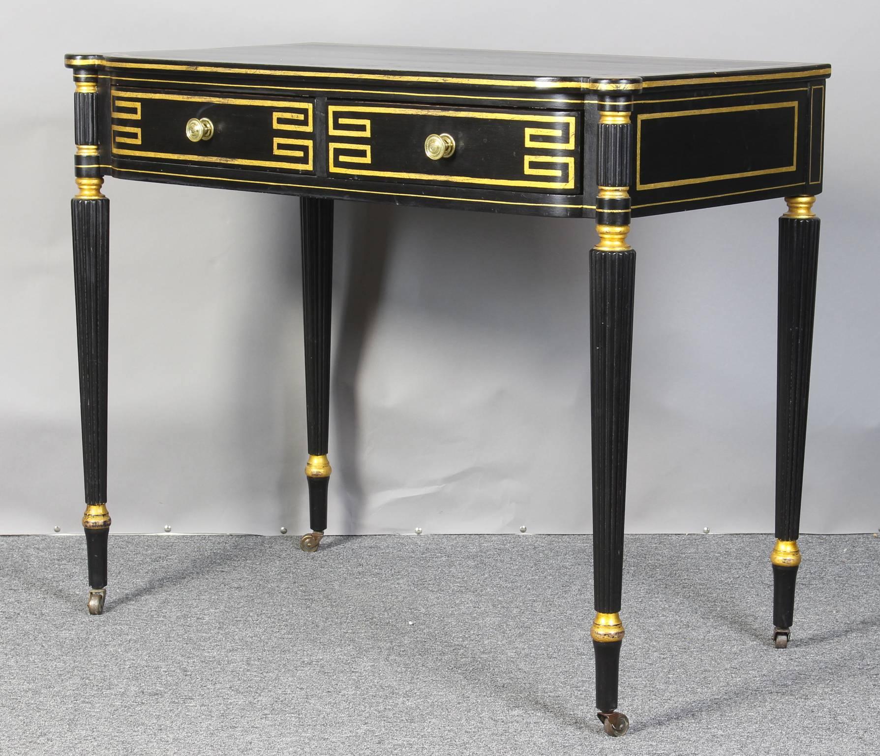 An elegant Regency style ebonized and gilt decorated console table having two drawers supported by reeded tapering legs terminating in casters.