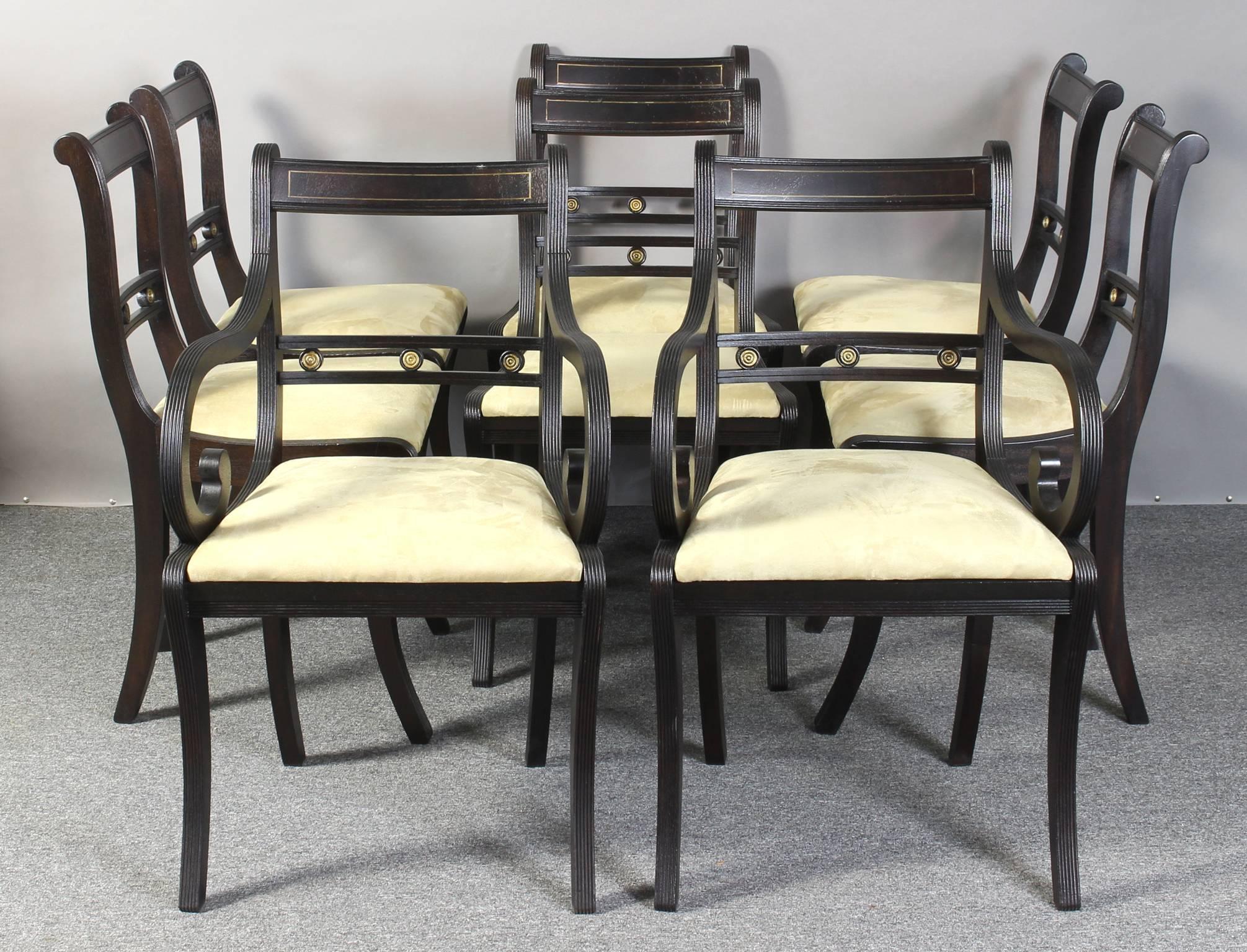 A set of eight solid mahogany Regency style dining chairs comprising two arms and six sides. The chairs, inset with brass accents, have a hand-rubbed ebony finish allowing the rich mahogany grain to show through. With reeded saber legs and slip