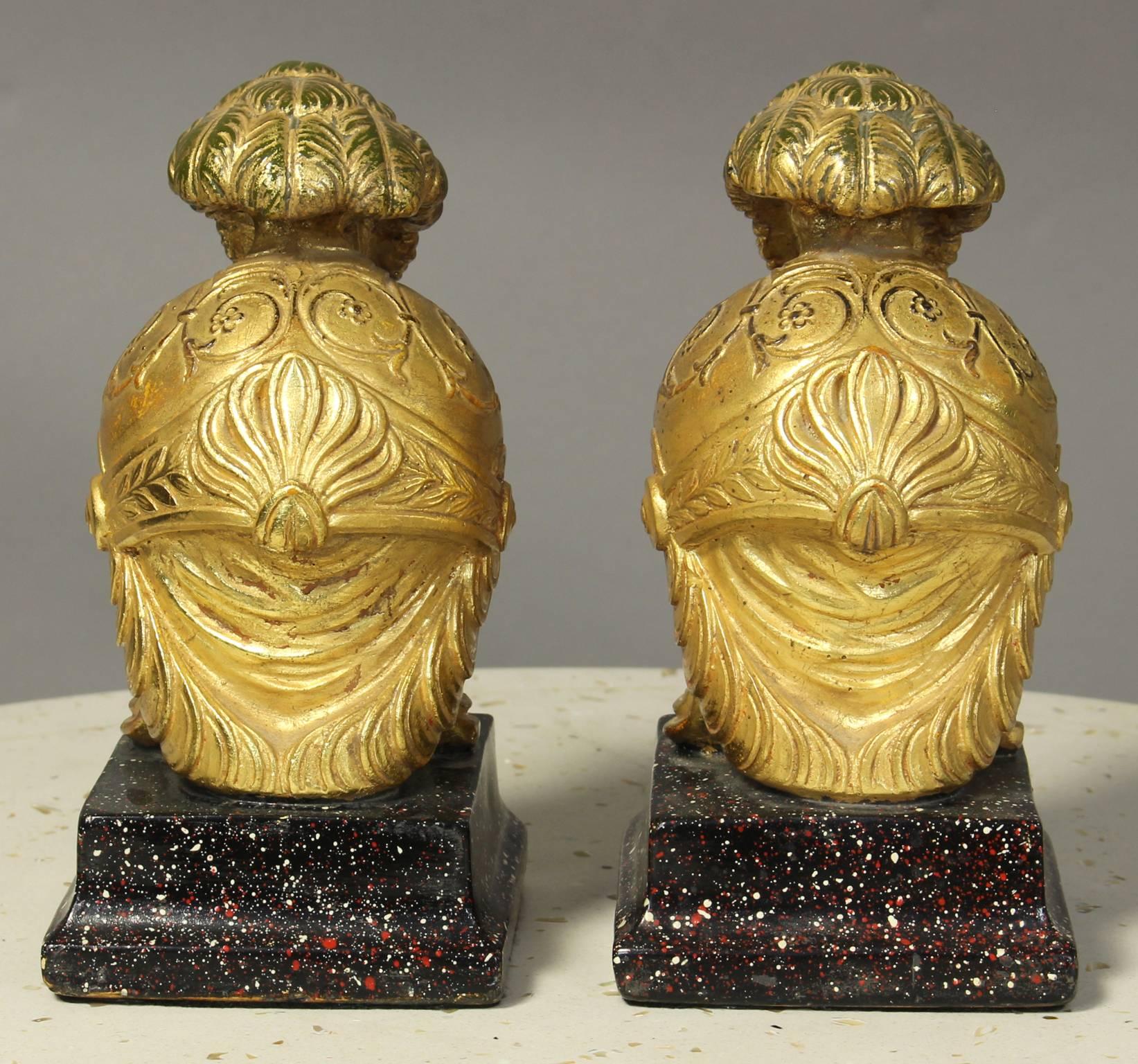 A delightful pair of Italian mid-20th century gilt and paint decorated Roman helmet bookends on faux stone bases made by Borghese.