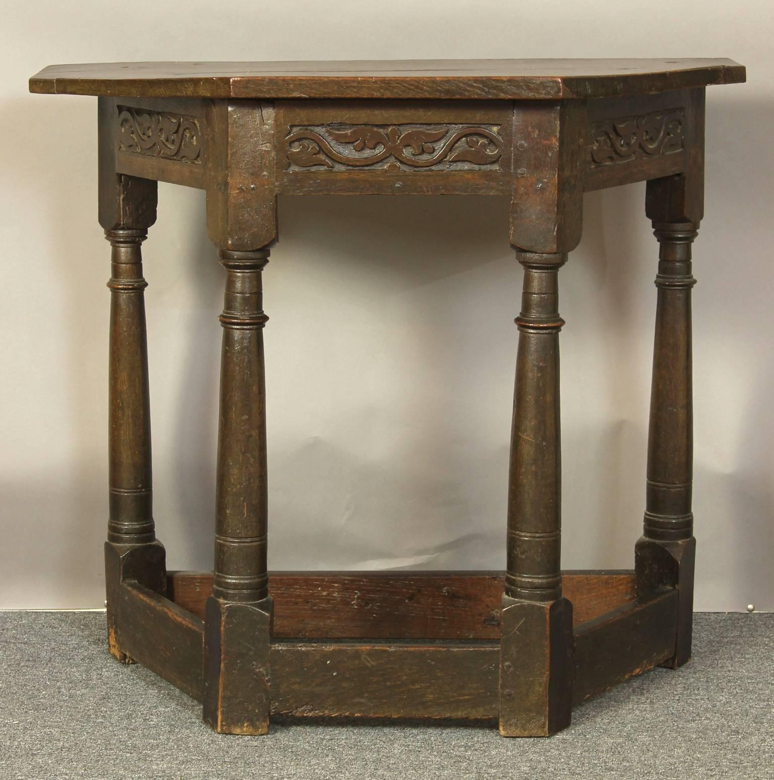 A small and charming early 18th century English oak console table with plank top, above a carved frieze with turned legs joined by stretchers.