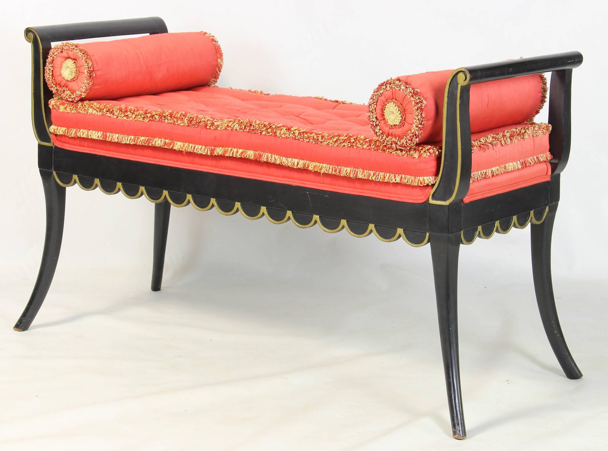 A charming ebonized Hollywood Regency window seat or bench with delicate flared legs and scalloped skirt and traces of old gold paint.  