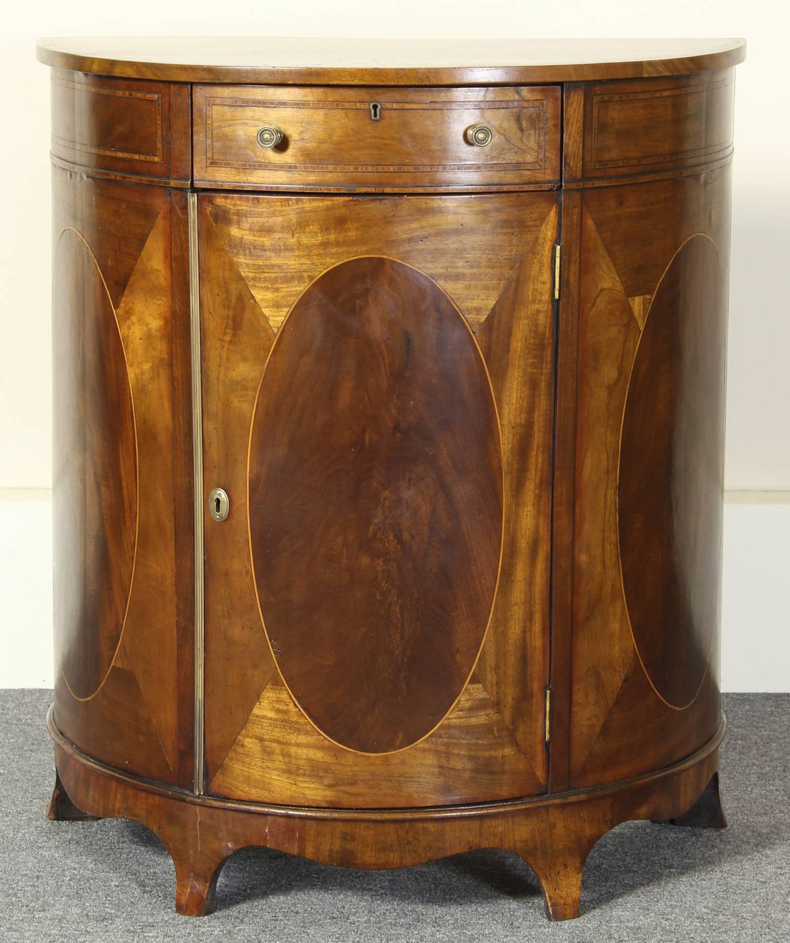 A late 19th C. English mahogany Sheraton style demi-lune silver cabinet of rare small size. The single drawer above the cabinet door containing two deep felt-lined silver drawers with double compartments. 