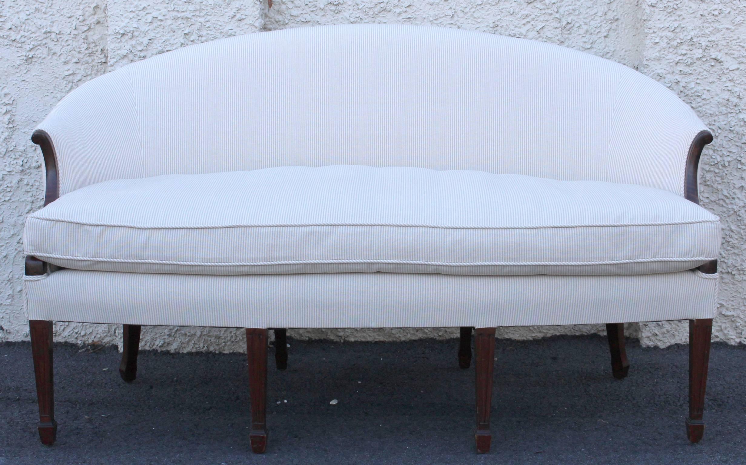 A small and elegant early 19th century Sheraton mahogany sofa with gracefully curved back. The sofa is newly upholstered in pale cream and off white cotton ticking fabric with a down-filled loose cushion.