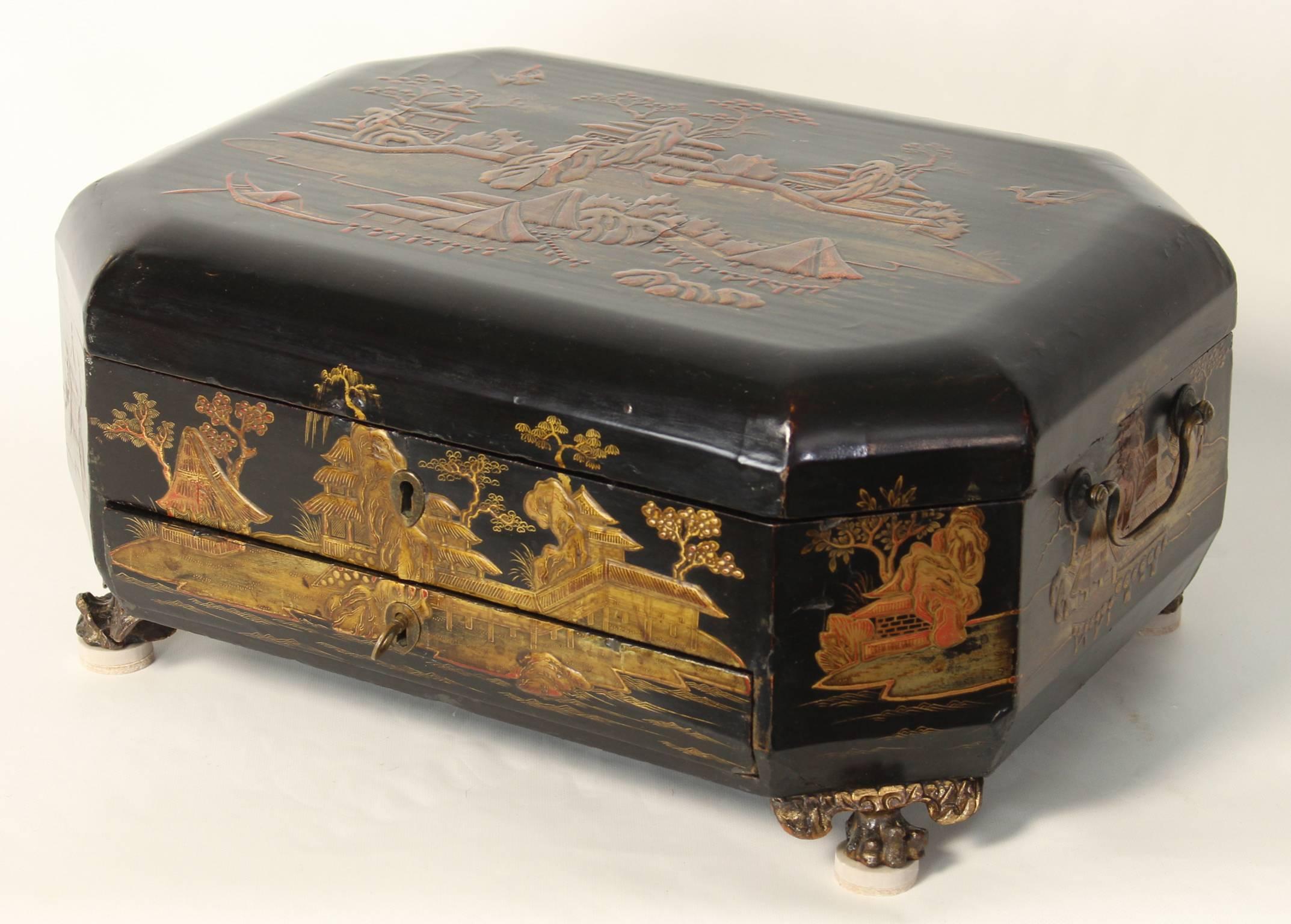 A mid-19th century black lacquer Chinese Export sewing box with traditional raised gilt decoration resting on carved paw feet.