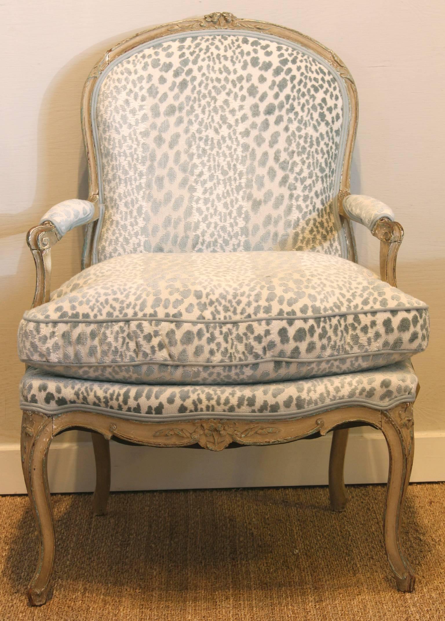 A late 18th century French paint decorated upholstered open armchair with shaped back, padded scroll arms and loose cushion seat, raised on molded cabriole legs. The chair is newly upholstered in a luxurious ice blue leopard print linen velvet