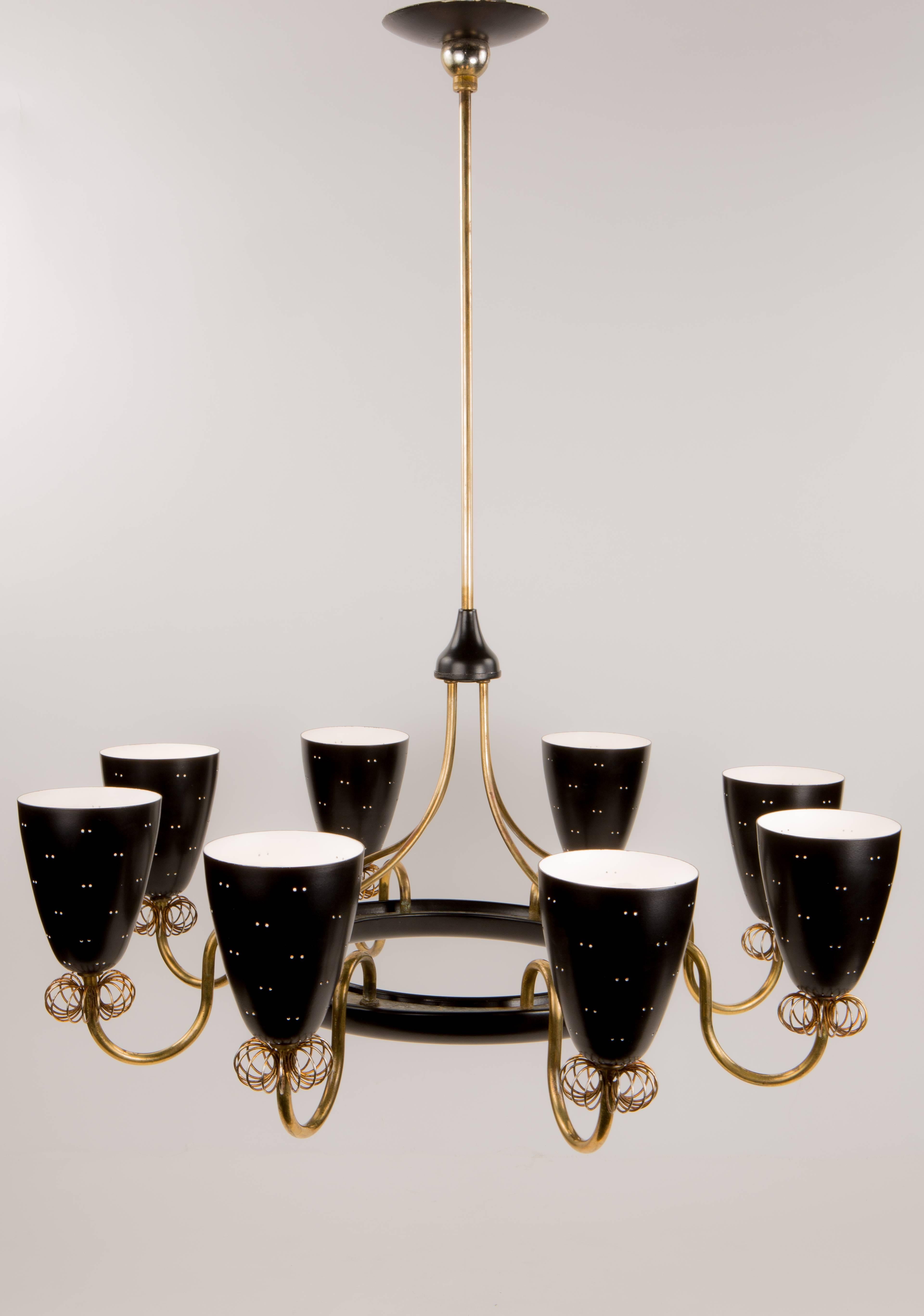 An exceptional and impressive eight-light chandelier designed by Paavo Tynell for Lightolier decorated with eight polished brass arms each adorned with a black painted perforated metal shade and further embellished with his signature coil decoration