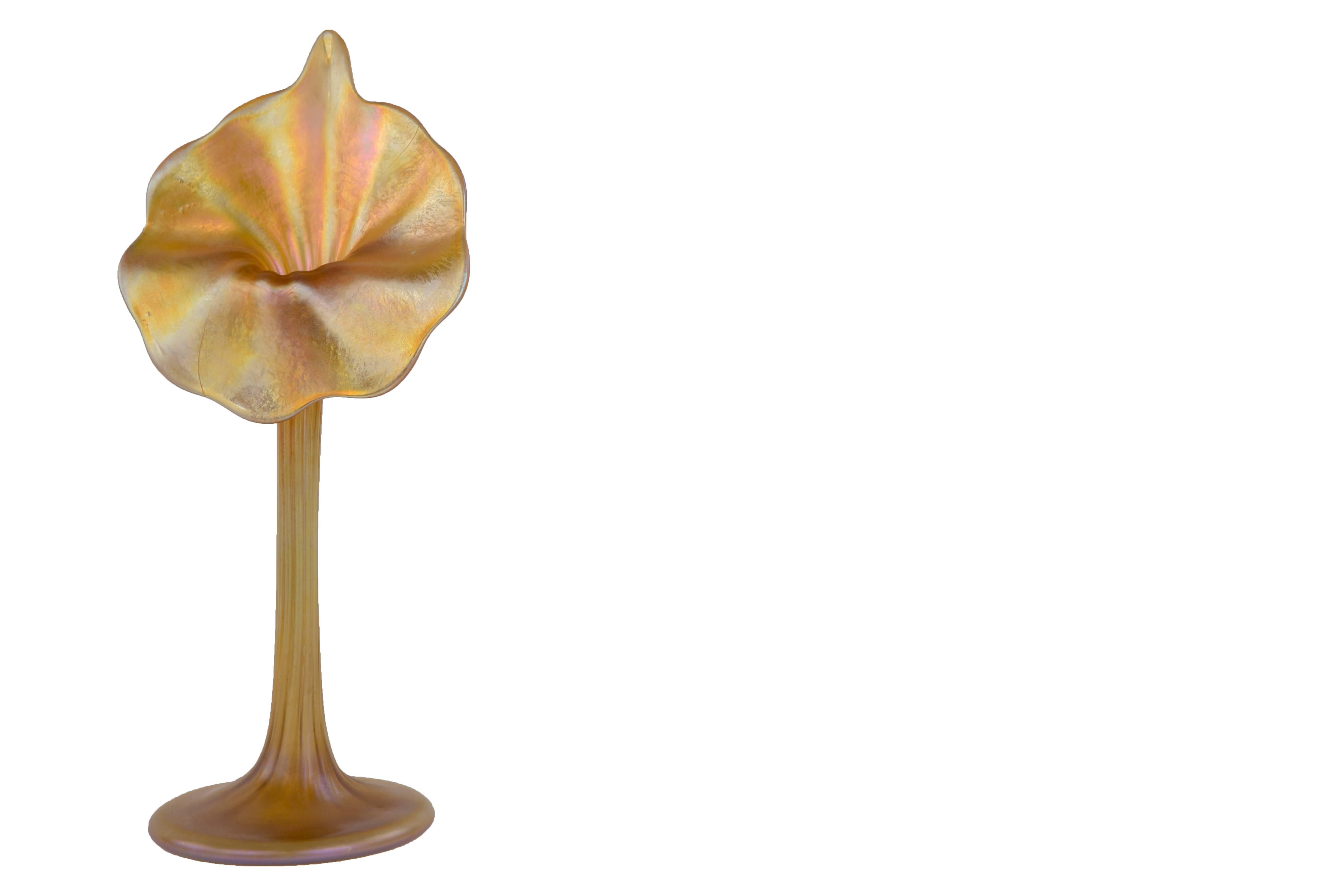 An American Art Nouveau blown glass Favrile Jack-in-the-Pulpit Flowerform Vase by, Tiffany Studios decorated in an iridescent gold coloration with ribbed stem and uniform opening. The vase is signed, 
