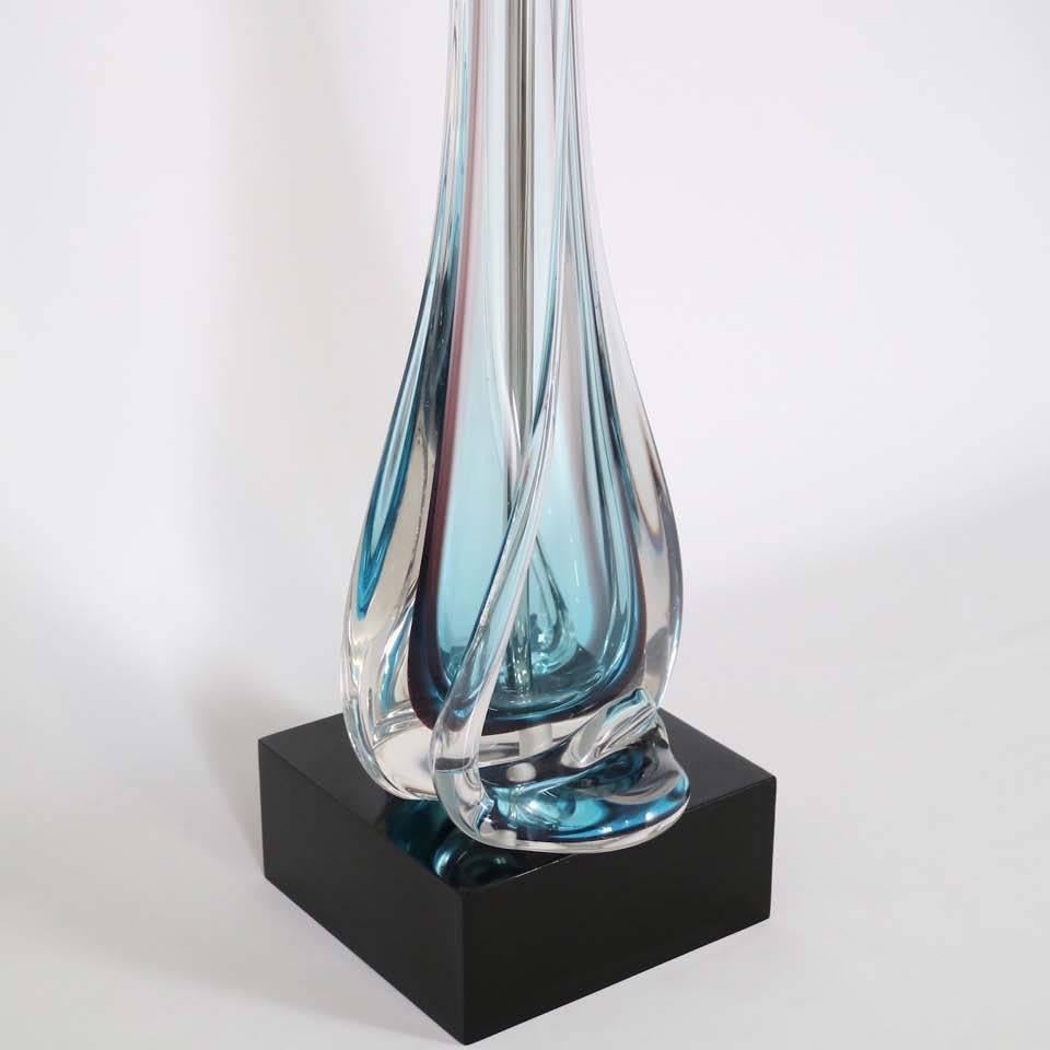 An elegant blue Murano glass table lamp, produced in Italy, circa 1950s by Archimede Seguso, with double cluster socket in a plated nickel, over body styled in the iconic elongated shape, using the 'sommerso technique' and mounted on a black