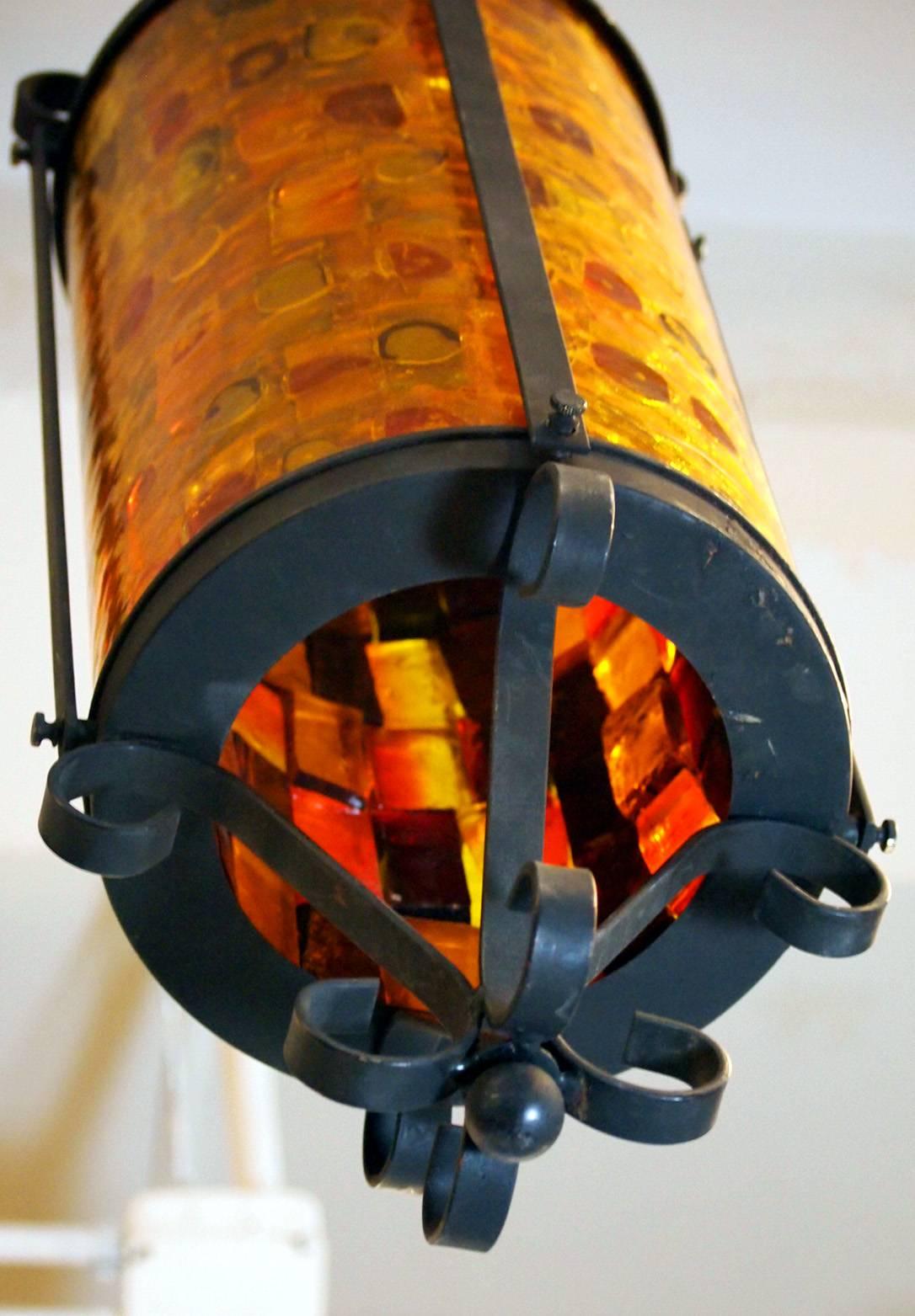 These four vintage cathedral pendant come with multicolored cylindrical glass shades, composed of red, orange and yellow blocks, each set in a metal frame, with metal scroll work, giving the light fixtures a very Gothic appearance. Each requires a