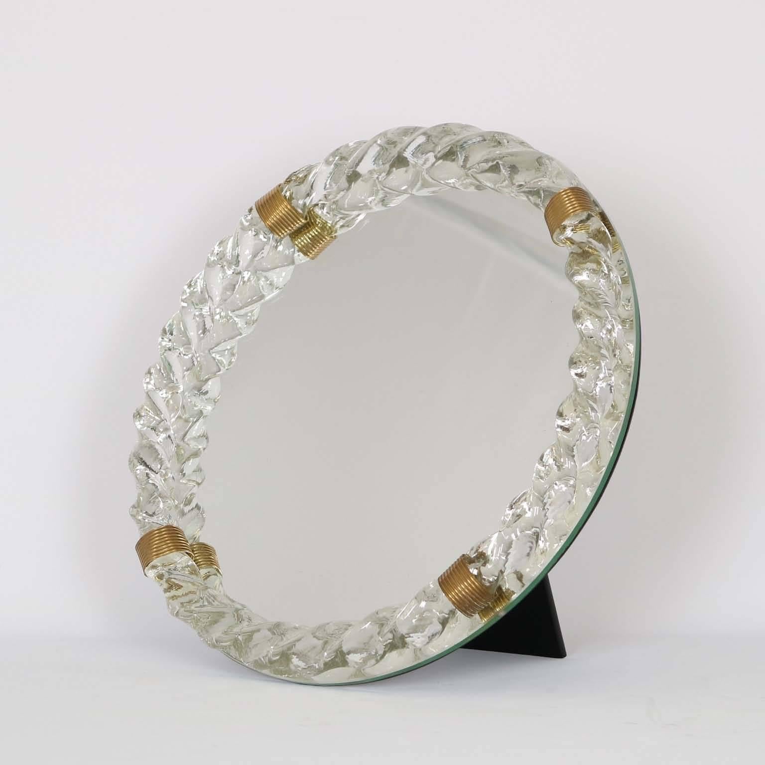 An Italian round table top mirror, design attributed to Gio Ponti, produced circa 1930s-1940s, with Murano glass twisted frame by Venini, accented with brass bands, against ebonized wood. Very good vintage condition, wear consistent with age and use.