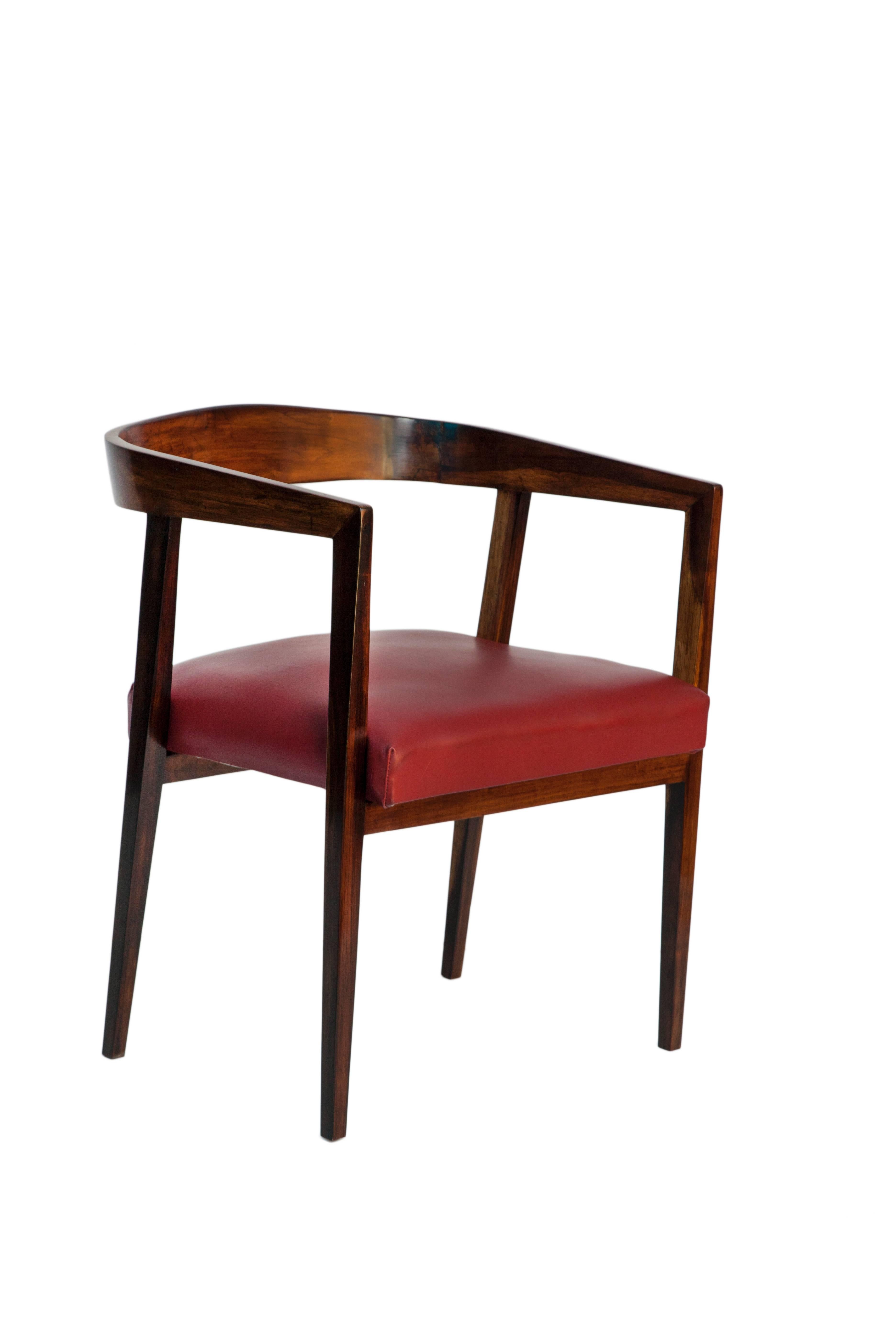 A set of four circa 1950s dining chairs designed by Joaquim Tenreiro, each in Brazilian jacaranda wood with curved back and arms, seats upholstered in red leather. Excellent vintage condition, seats recently reupholstered.