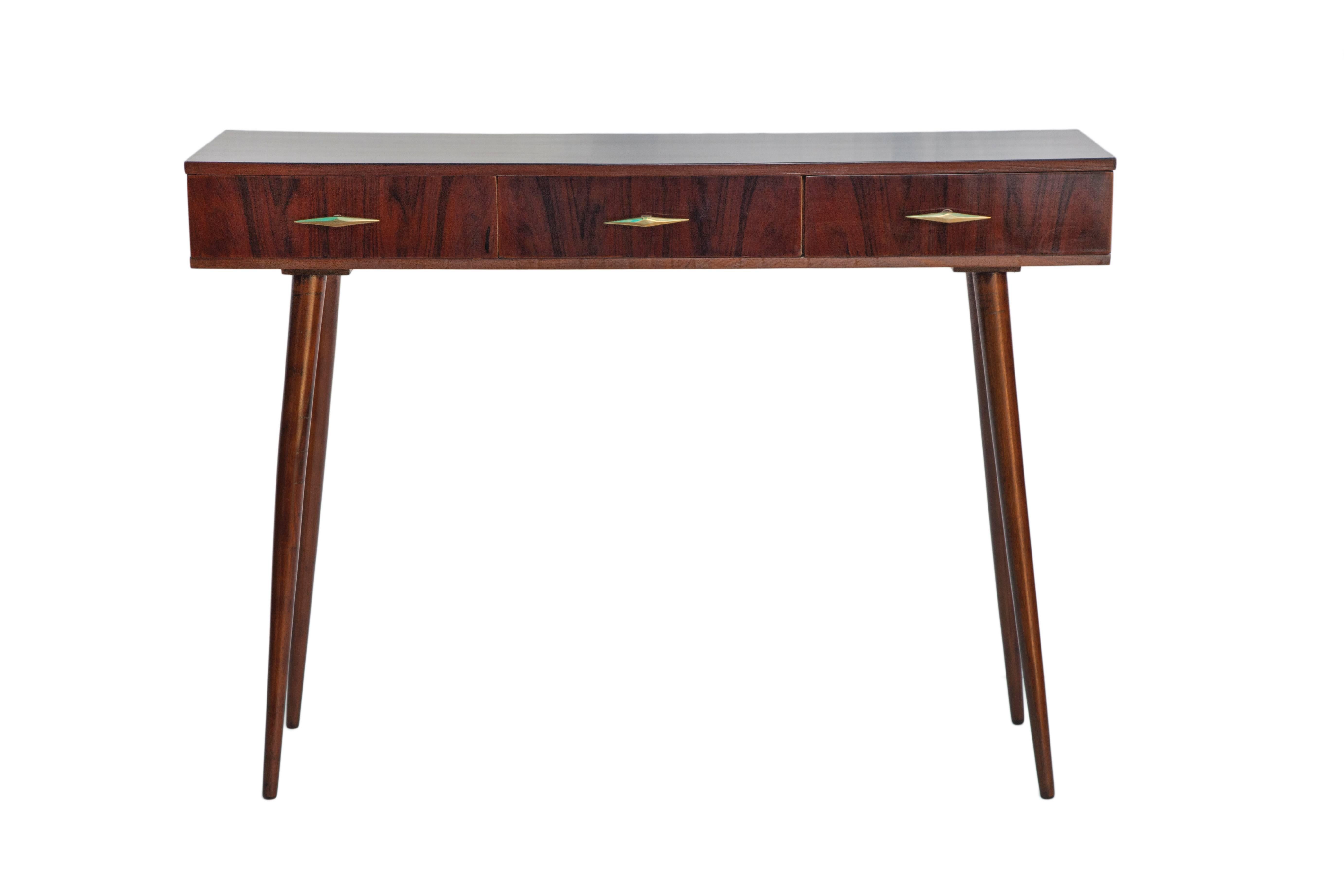 A Brazilian console table, in deep jacaranda wood, including three drawers to the front, each with diamond shaped pull handle, raised on round tapered legs, circa 1950s. This piece remains in excellent vintage condition, wear consistent with age and