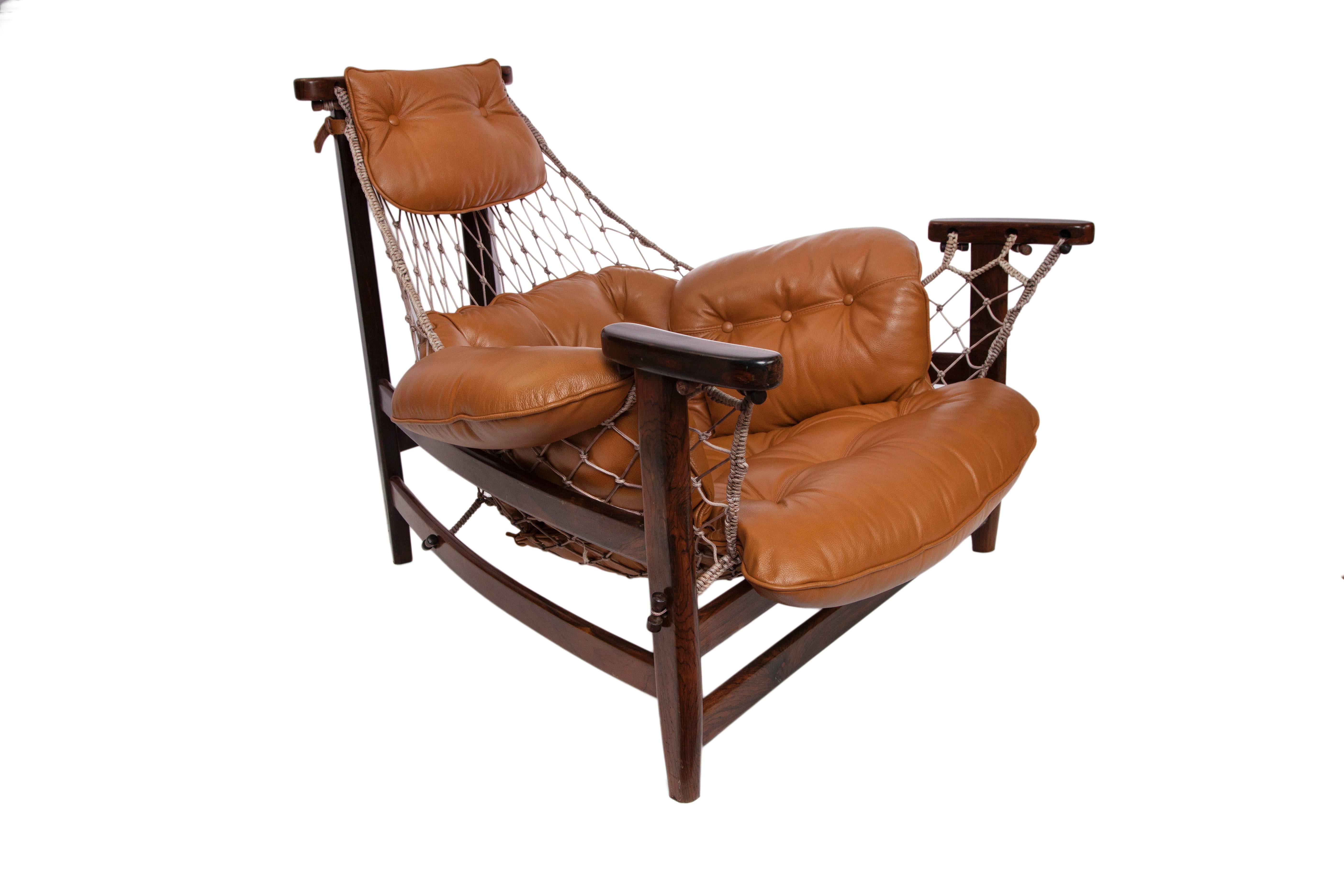 A 1960s lounge chair and footstool by French designer Jean Gillon, with tufted leather upholstery and rope hammock slings, against Brazilian jacaranda wood. Excellent vintage condition, consistent with age and use.

Dimensions:
Footstool -