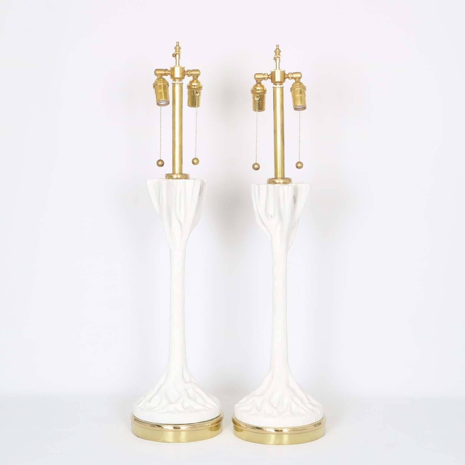 A pair of carved wood faux bois table lamps with plaster finish  in the manner of John Dickinson, produced in the United States, circa 1970s, mounted on brass bases.  The lamps are in excellent vintage condition, fully restored with new wiring and