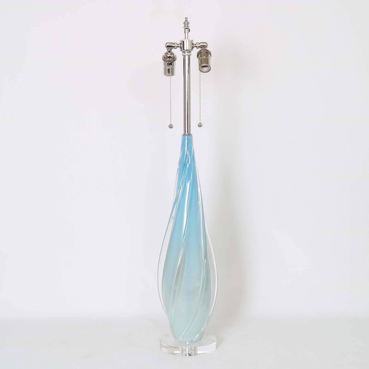 Opaline with blue in degrade Murano glass lamp by Seguso, with clear applied glass vertical swirling ribs. Mounted on a Lucite base. The noted height is top the finial. The height to the top of the glass is 22.5 in (57 cm). Fully restored with all