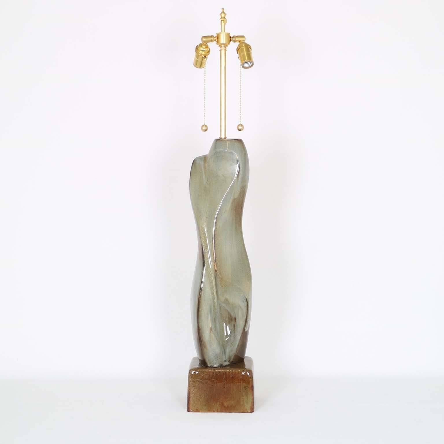 Tall and sculptural pottery lamp in the manner of Mariana von Allesch, with beautiful pigmentation in a celadon and ocres glaze. The noted height is to the finial. The height to the top of the ceramic body is 26.5 in (67 cm). Fully restored with all