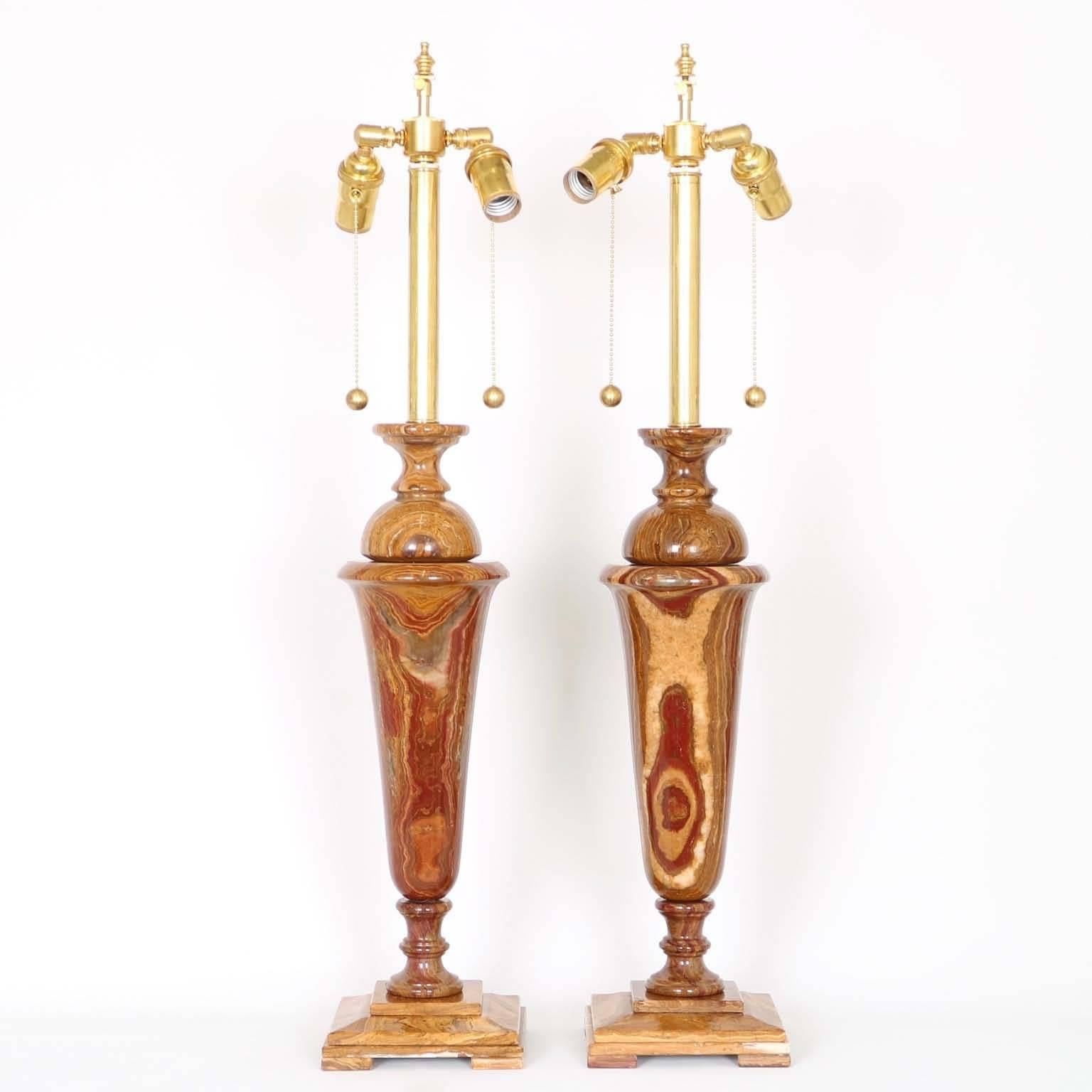A stunning pair of Italian table lamps in red volcano onyx with a classical design. The noted height is to the finial, height to the top of each onyx body is 20.5 in (52 cm). Fully restored with all new wiring and hardware, including a double socket