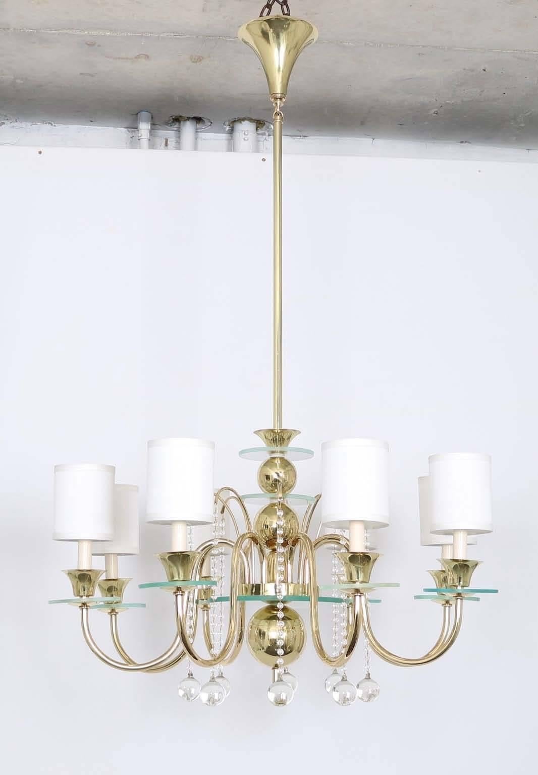 A fully restored circa 1950s chandelier, designed in the manner of Tommi Parzinger, stylistically streamline moderne, brass frame with stacked ball motif and tapered conical forms, eight lights on curved scroll arms, with decorative glass bobeches,