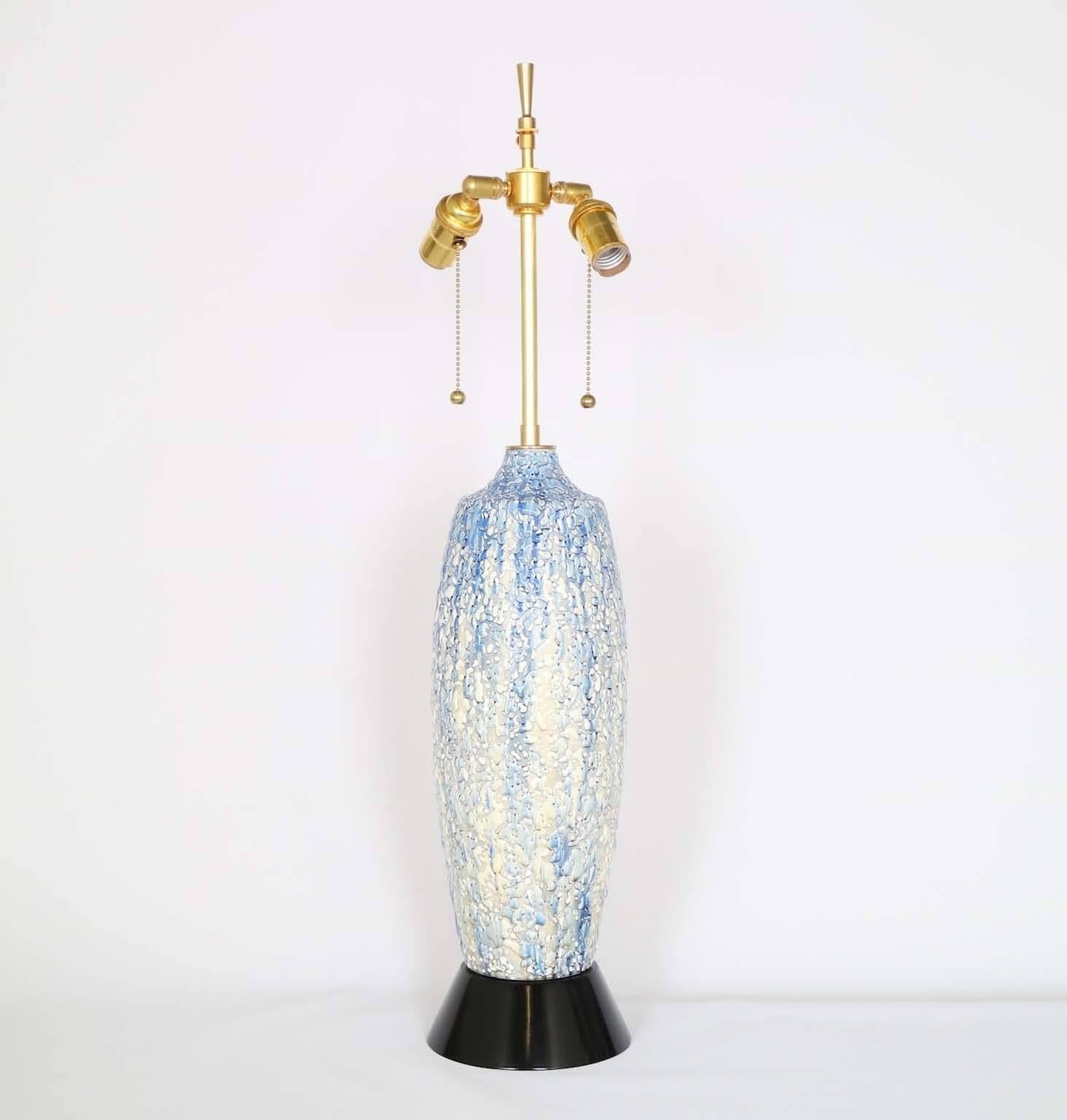 A Mid-Century Modern blue and white drip glaze table lamp with textured finish, mounted on a black ebonized wood base, produced circa 1950s. The noted height is to the finial; the height to the top of the ceramic body is 19 in (48 cm). Excellent