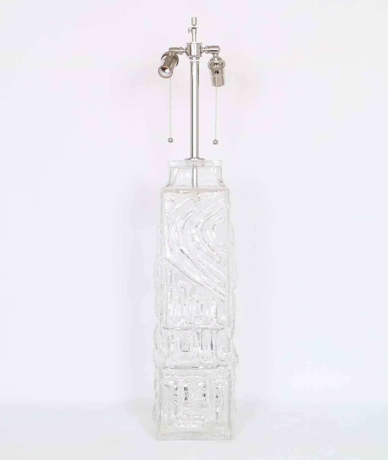  A single Swedish glass table lamp by the Pukeberg Glass Company, produced circa 1970s, the clear sculptural glass exceptionally crafted with relief patterns. The noted height is to the finial, the height to the top of the glass body is 24 in (61