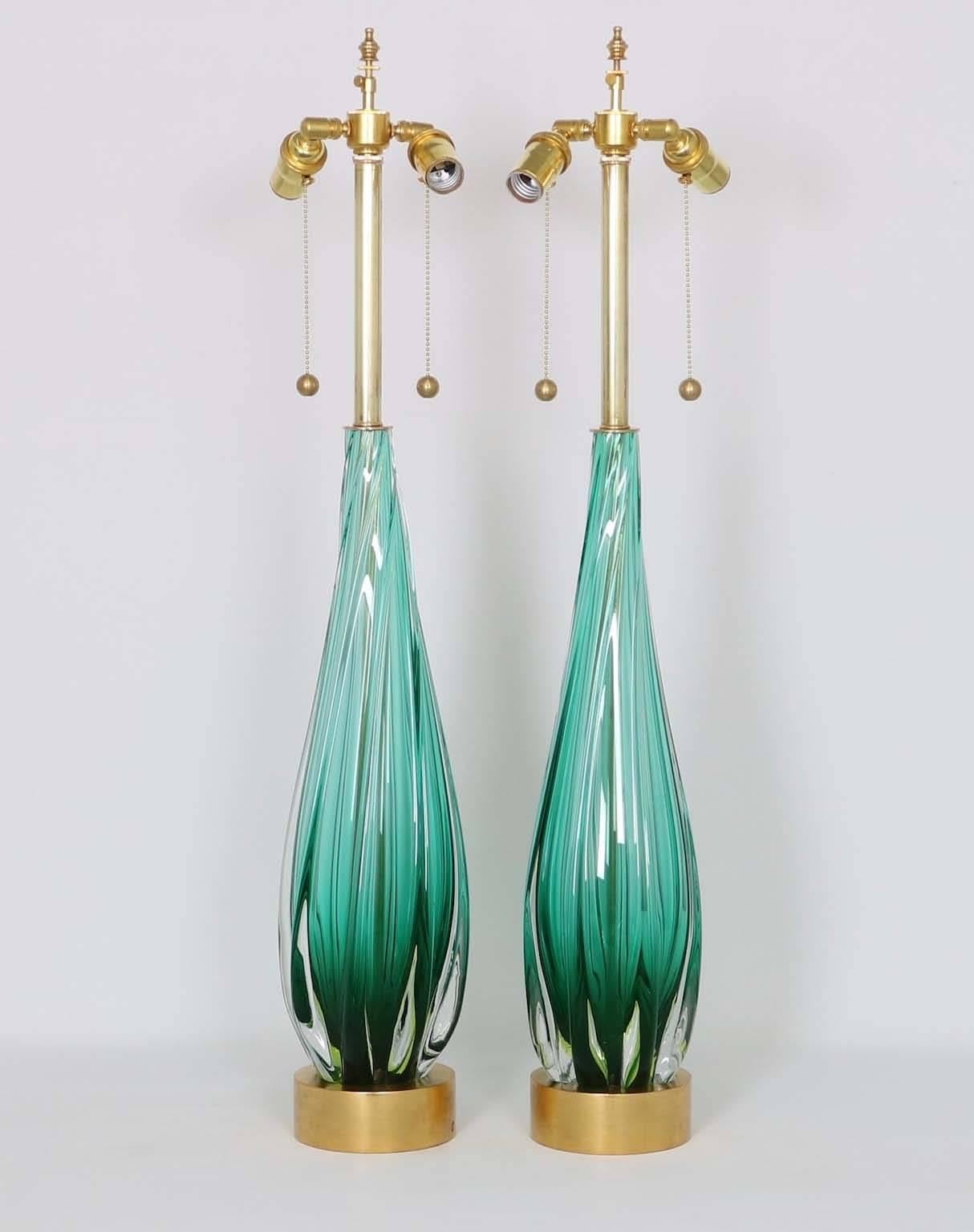 A pair of Mid-Century Modern Murano glass lamps by Seguso, produced circa 1950s, each drop form in green with clear Sommerso layer, mounted on a gilded wood base. The noted height is to the finial, the height to the top of the glass body is 23 in.