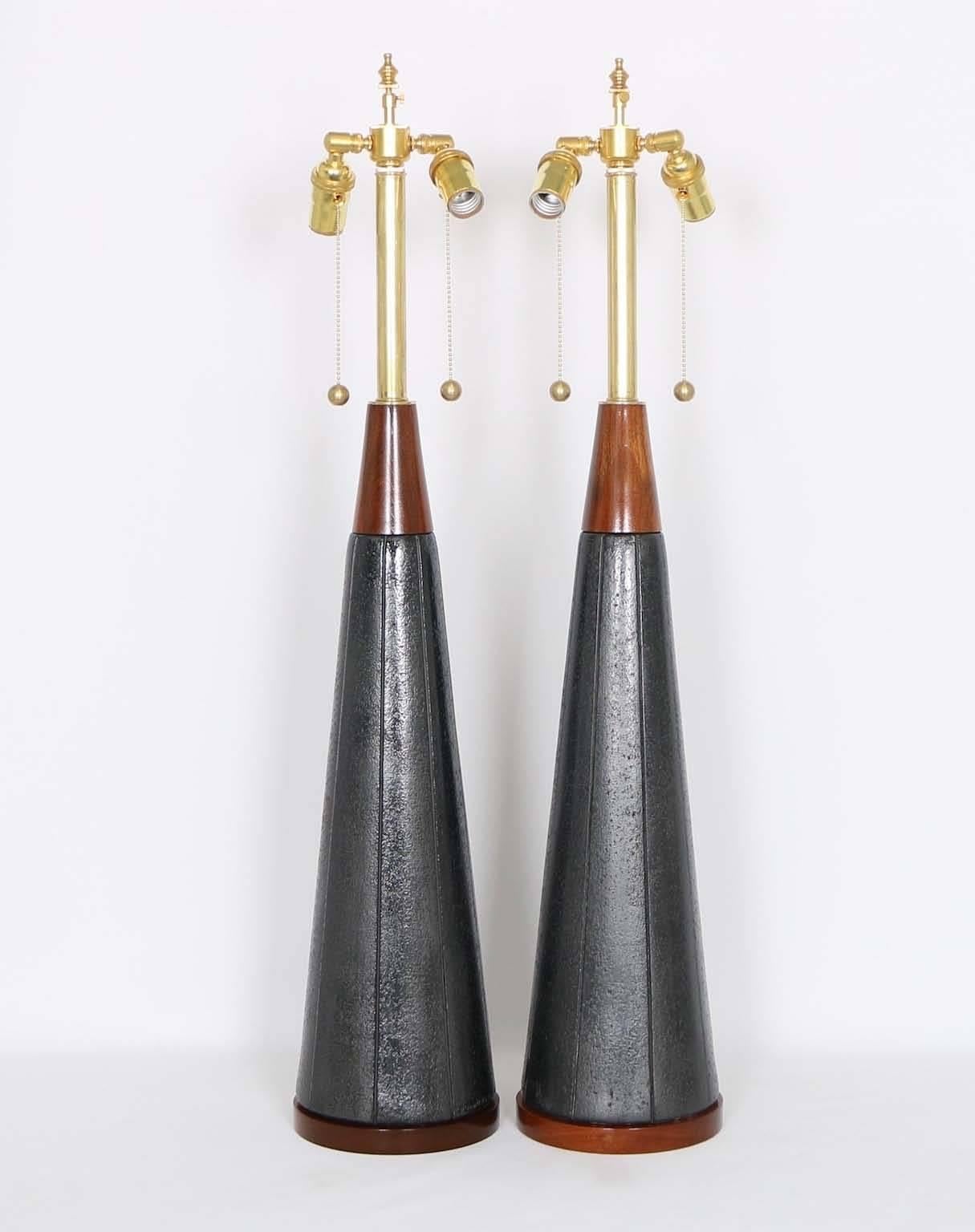 A pair of Mid-Century Modern table lamps, produced in the United States by Quartite Creative, of conical form in black-ash colored mottled ceramic with walnut accents. Marked and dated 1953 on the back of the ceramic body. The noted height is to the