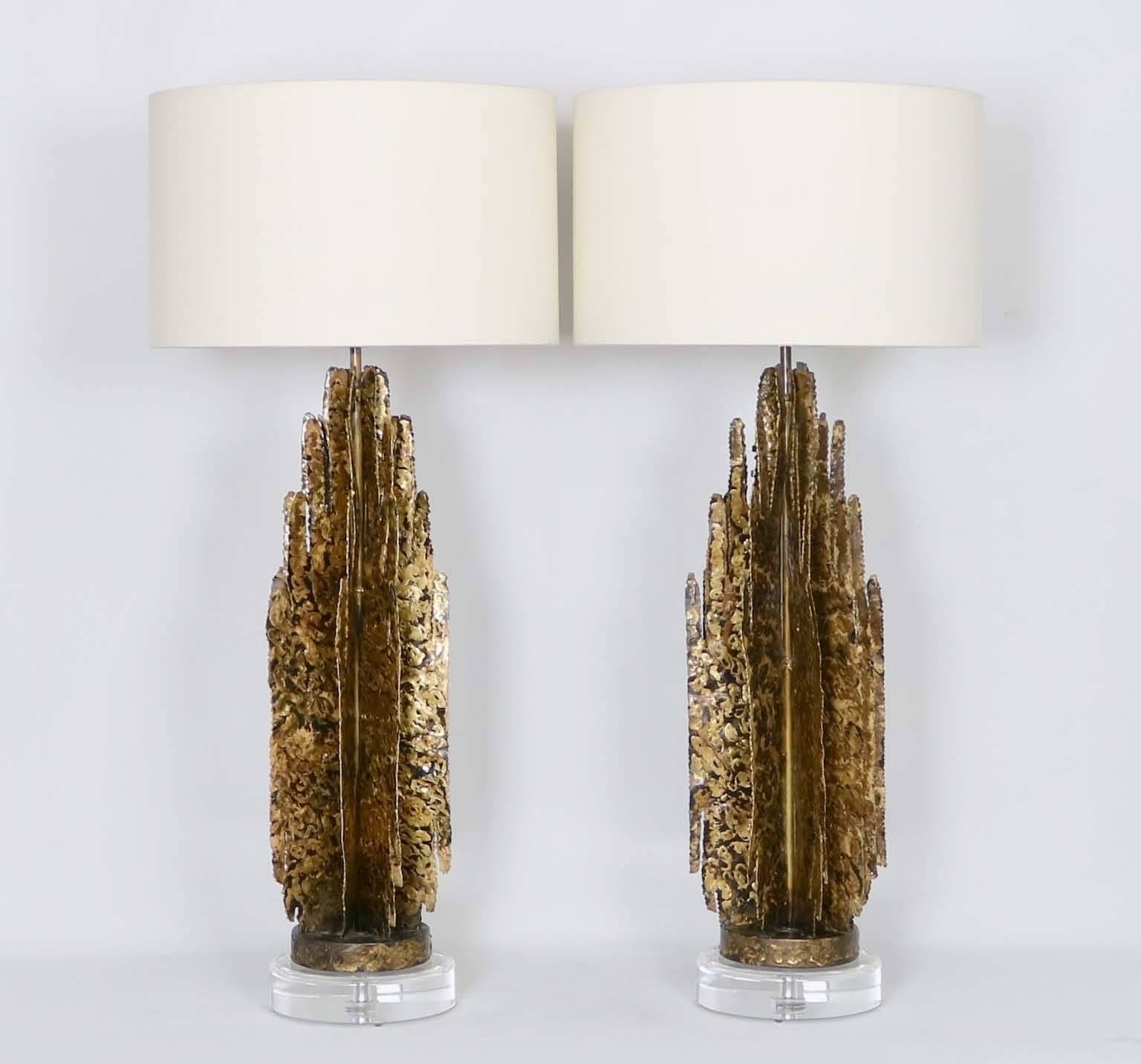 A pair of monumental Mid-Century Modern Brutalist abstract sculptural table lamps in the manner of Paul Evans, crafted of gilded tole with Lucite bases. The noted height is to the finial, the height to the top of the sculpture body is 29 in.