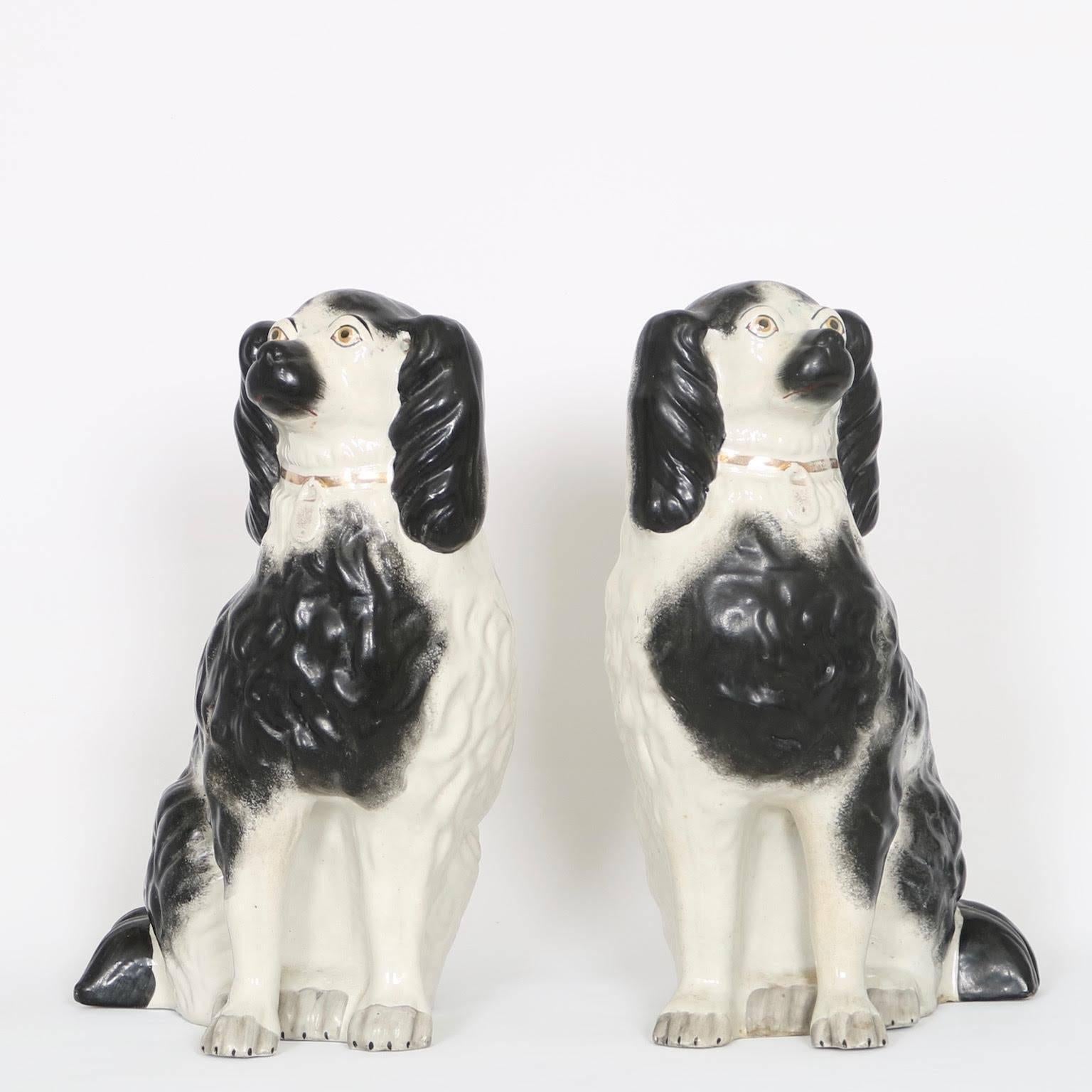 Pair of late 19th century Victorian era Staffordshire porcelain dogs, each with one leg separate from body, hand-painted with black and white accents and grey paws, gilding to the collars; no marks present. Excellent antique condition, wear and
