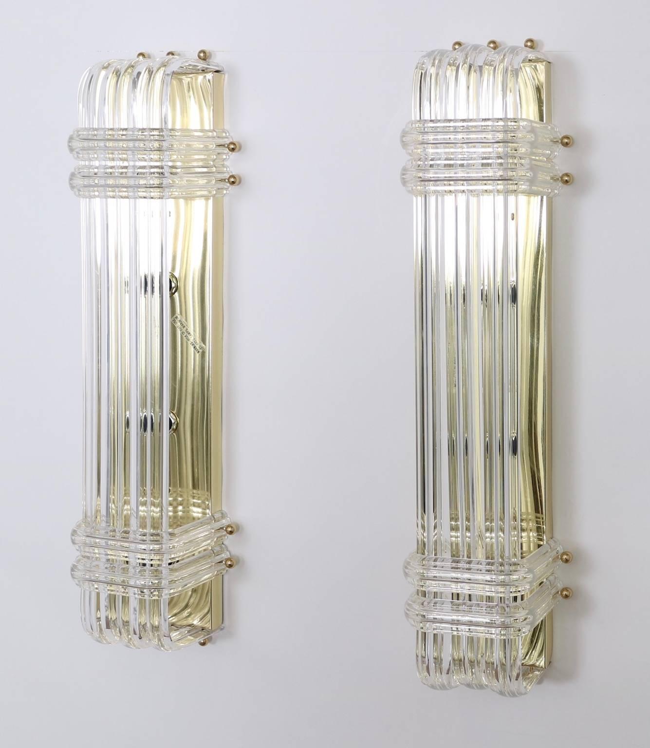 A pair of Mid-Century Modern era sconces, each in mint condition with overlapping Lucite ribbons, mounted to brass bases. Original labels included. Wiring and sockets to US standard, requires four candelabra base bulbs. Excellent vintage condition,