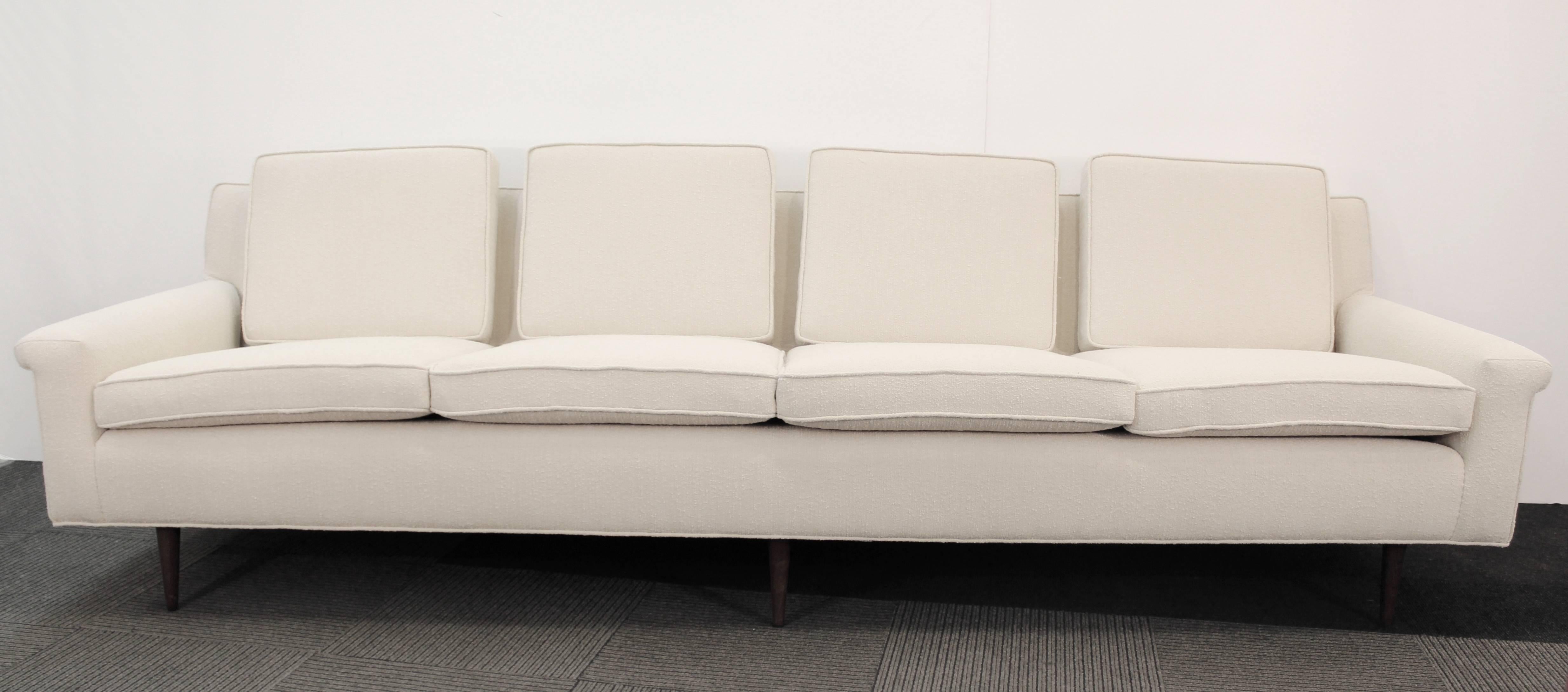 A four-seat sofa manufactured, circa 1960s by Thayer Coggin, upholstered in off-white bouclé fabric, raised on tapered walnut legs. Markings include original label. Excellent vintage condition, newly reupholstered.

110066