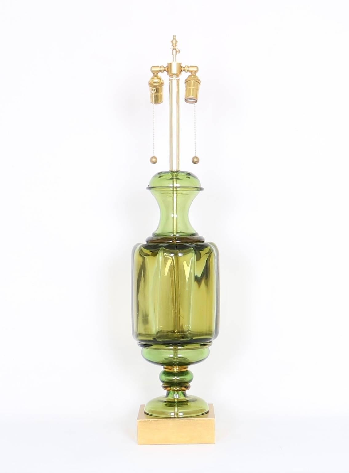 An Italian table lamp by Seguso for Marbro Lamp Company, with double cluster sockets on clear green urn form Murano glass body, raised on gilded wood base, circa 1950s. The dimensions provided reflect height to the finial; height to the top of the