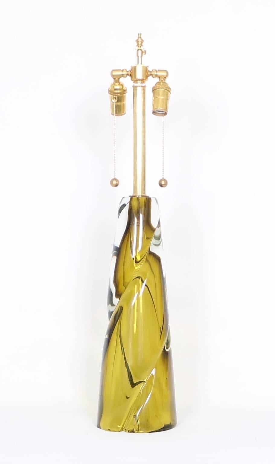 A Mid-Century Modern era table lamp by Seguso, produced in Italy circa 1950s, crafted of a single twisted piece of heavy chartreuse Murano glass with clear Sommerso layer. The noted height is to the finial; the height to the top of the glass body is