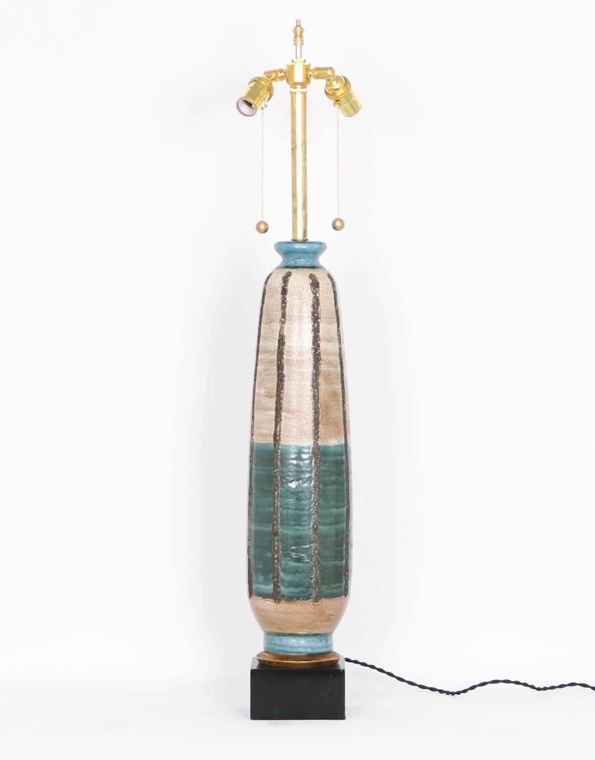 Tall Mid-Century Modern 1950s pottery lamp, with beautiful combination of colors and mounted on a gilt and ebonized wooden base, making it an entirely unique piece. The noted height is to the finial, the height to the top of the ceramic body is 26
