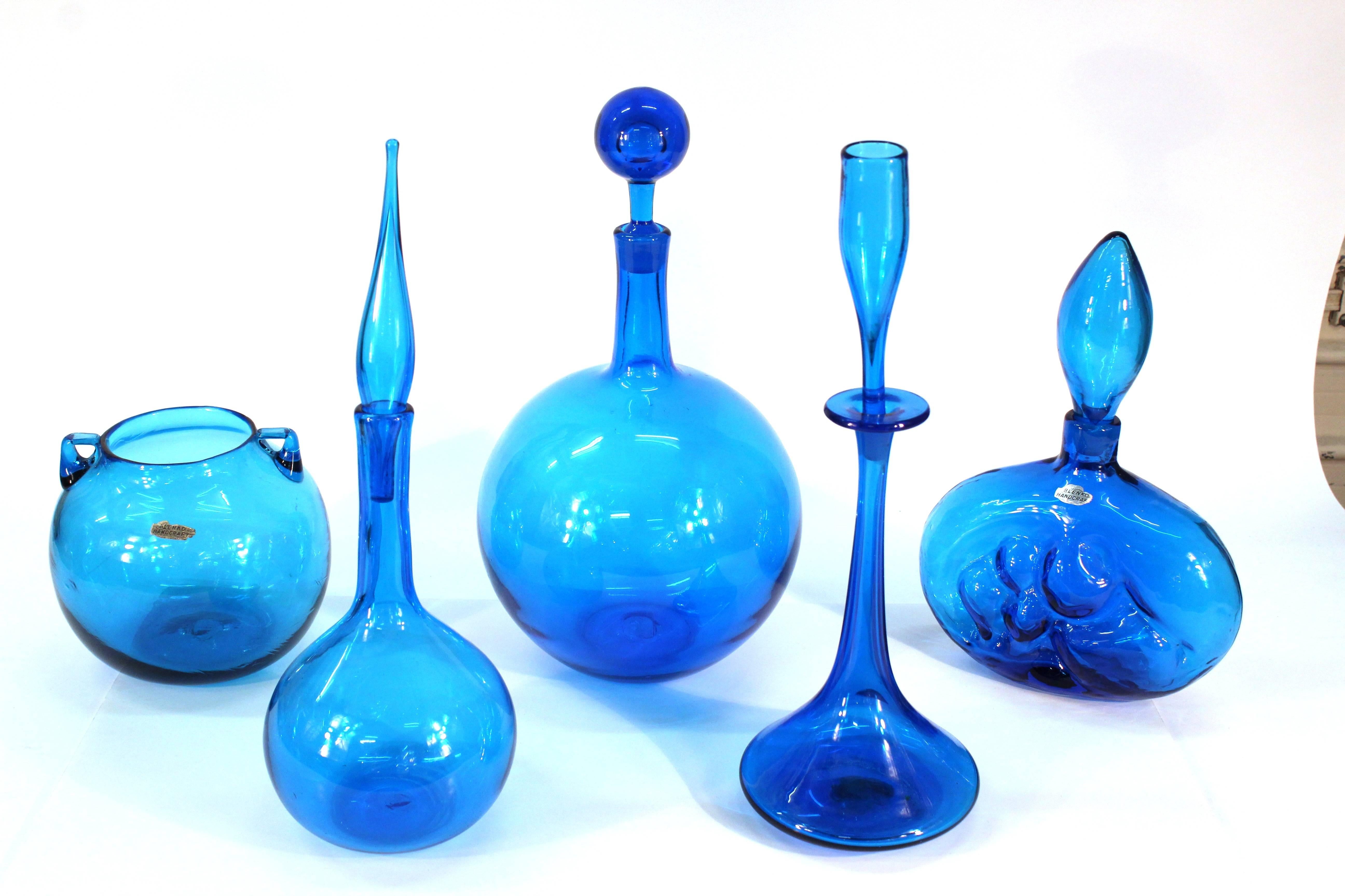 A group of five blown glass pieces by Blenko. Produced in Milton, West Virginia by Wayne Husted and Joel Myer. Available as a collection or individually, all pieces are uniquely numbered.

#16-08-02: Shot glass decanter with sticker, Turquoise