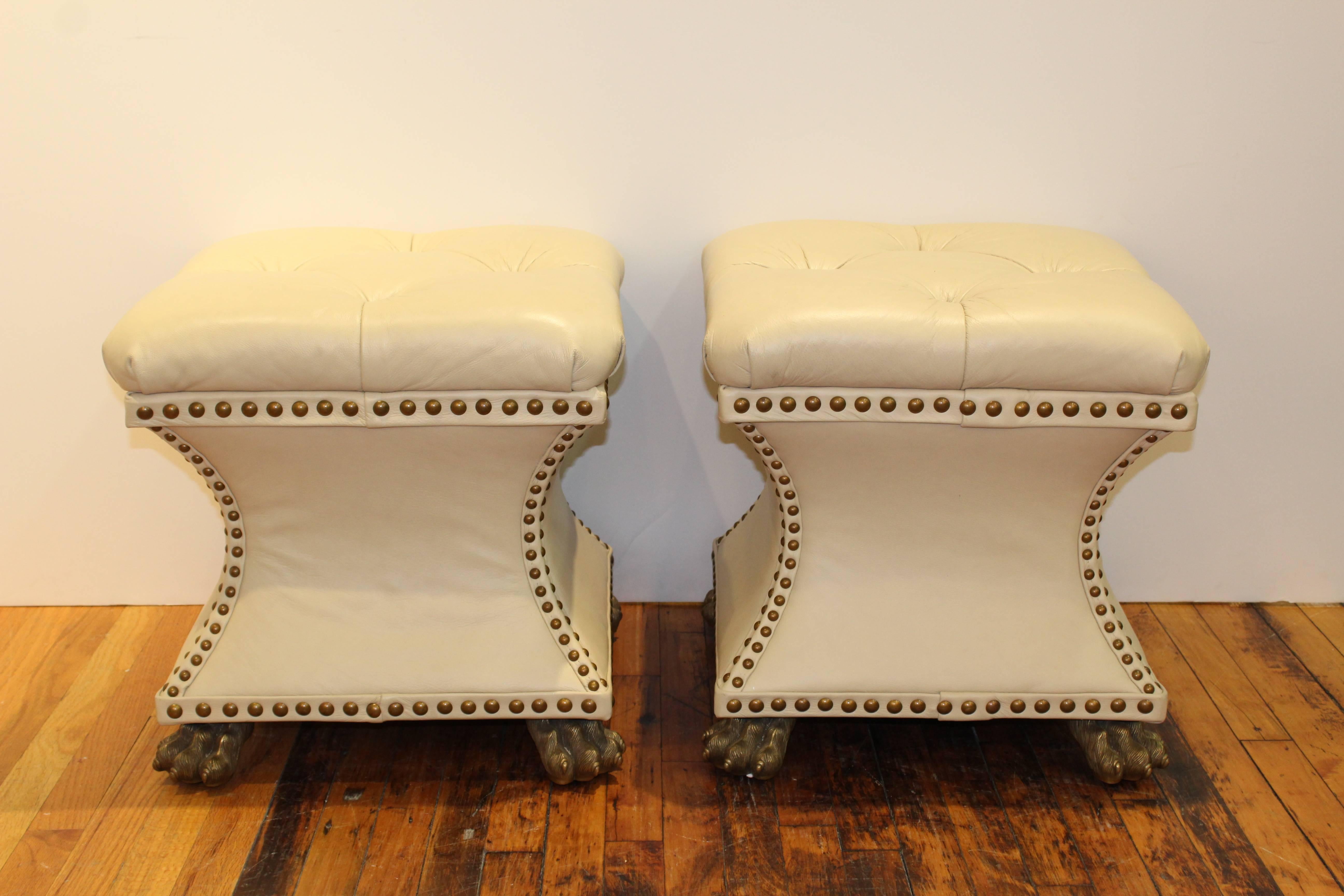 Pair of Hollywood Regency style benches by Maitland Smith. Upholstered in cream leather with brass hairy paw feet. In very good condition. 

110484