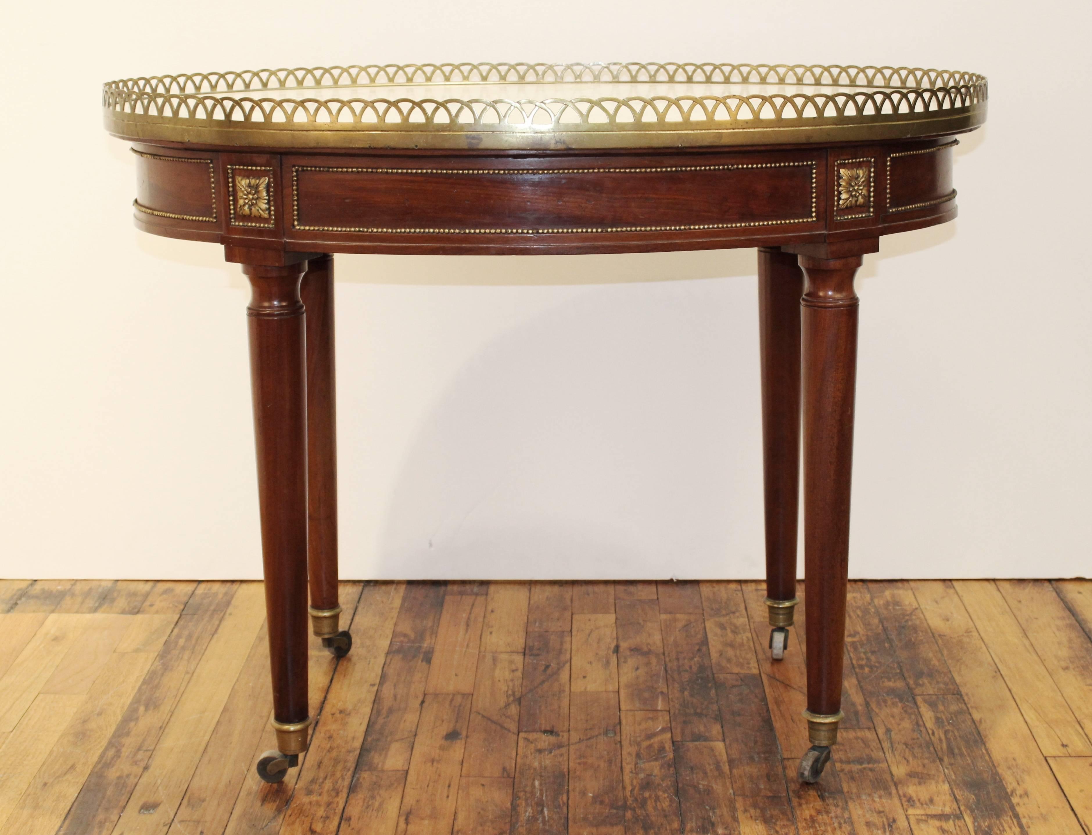 Mid-late 18th century side table by French cabinetmaker Georges Jacob (1739-1814, master 1765), oval galleried marble top on bronze-mounted mahogany base with bead trim border and rosettes; with casters. Markings include stamp [G. Jacob] with