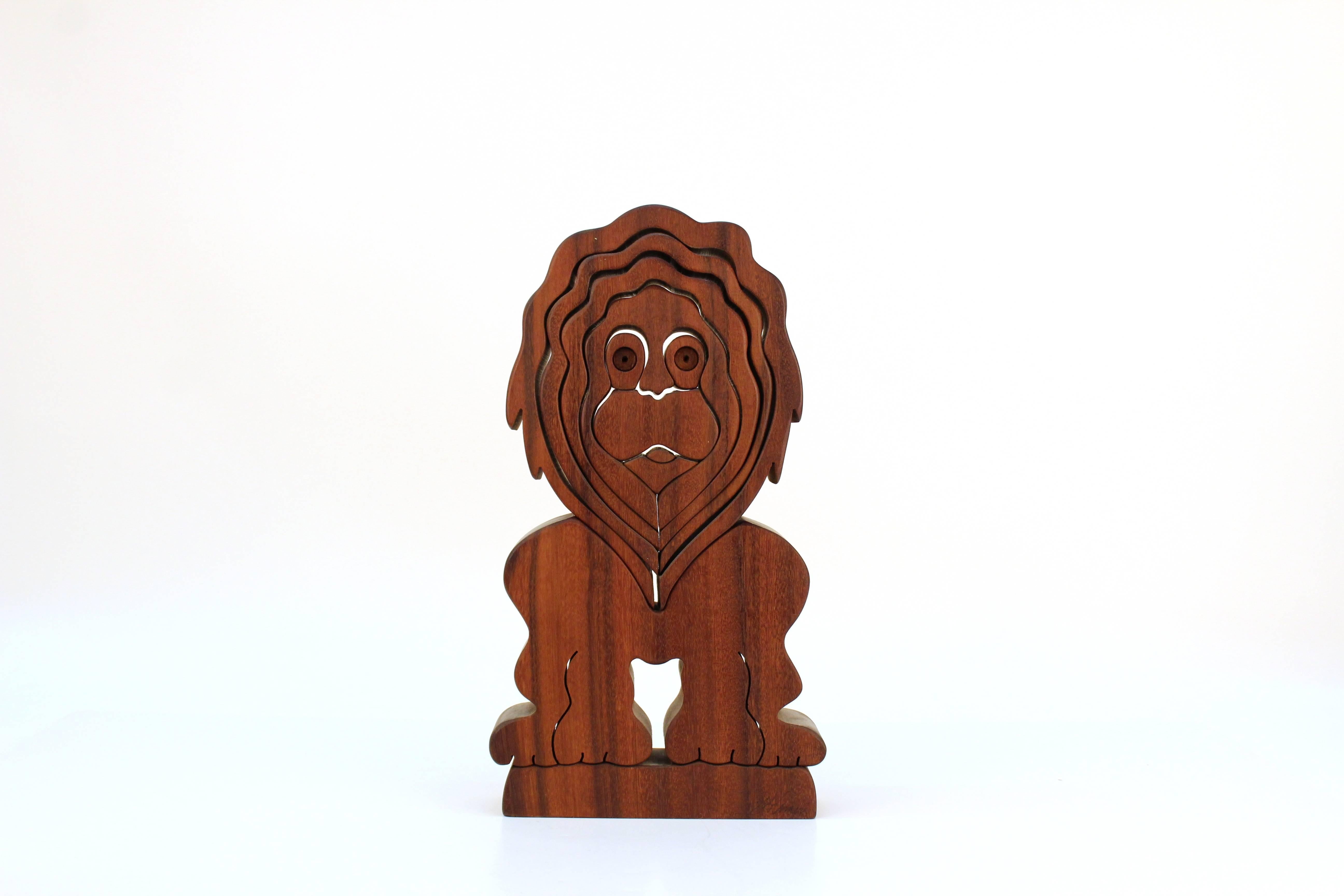 A wooden puzzle sculpture in the form of caricature lion by Bob Ameri. Made in rich dark wood, the sculpture comes completely apart for fun. Signed on base.

110487.
